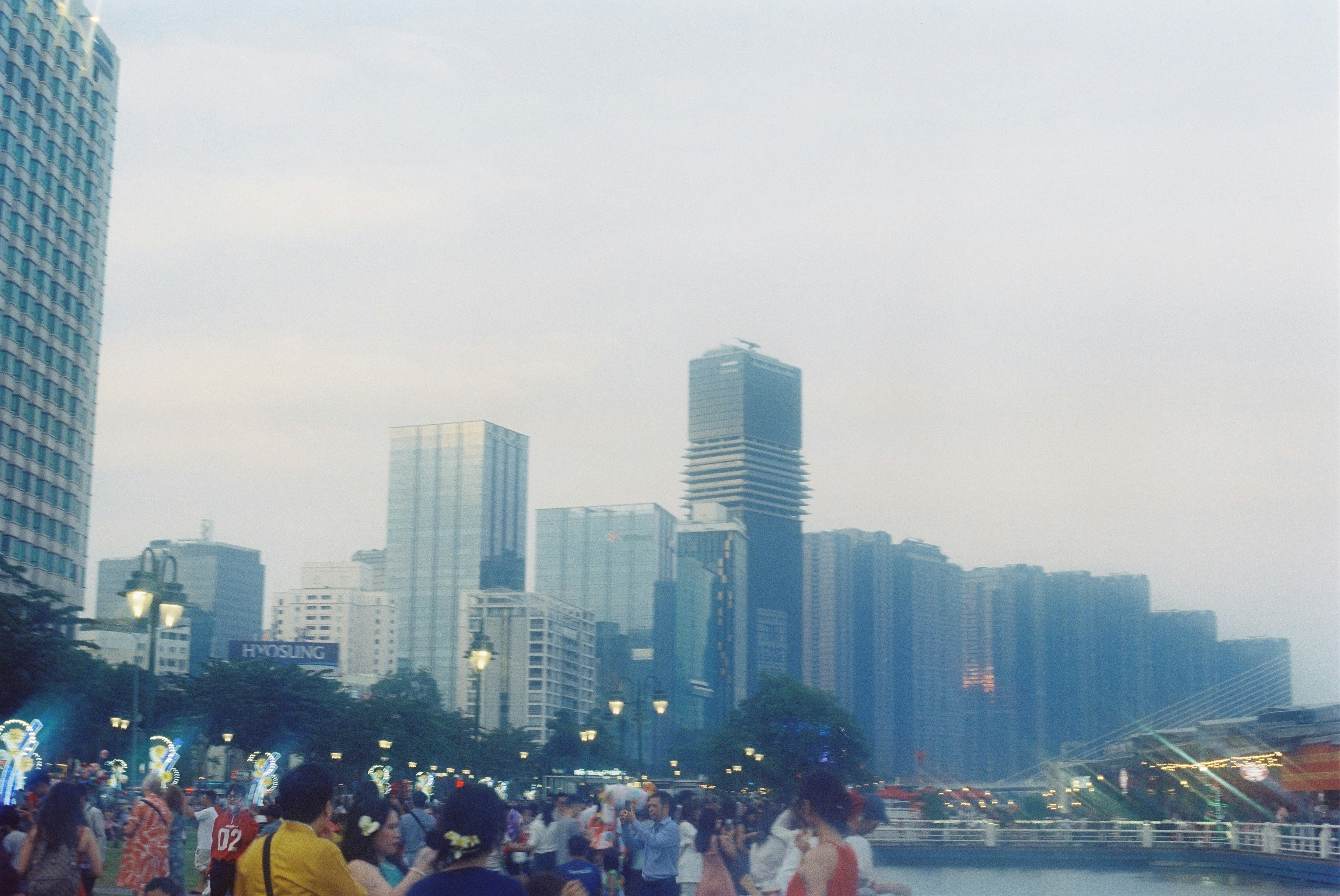 A group of people walking along a river next to tall buildings
