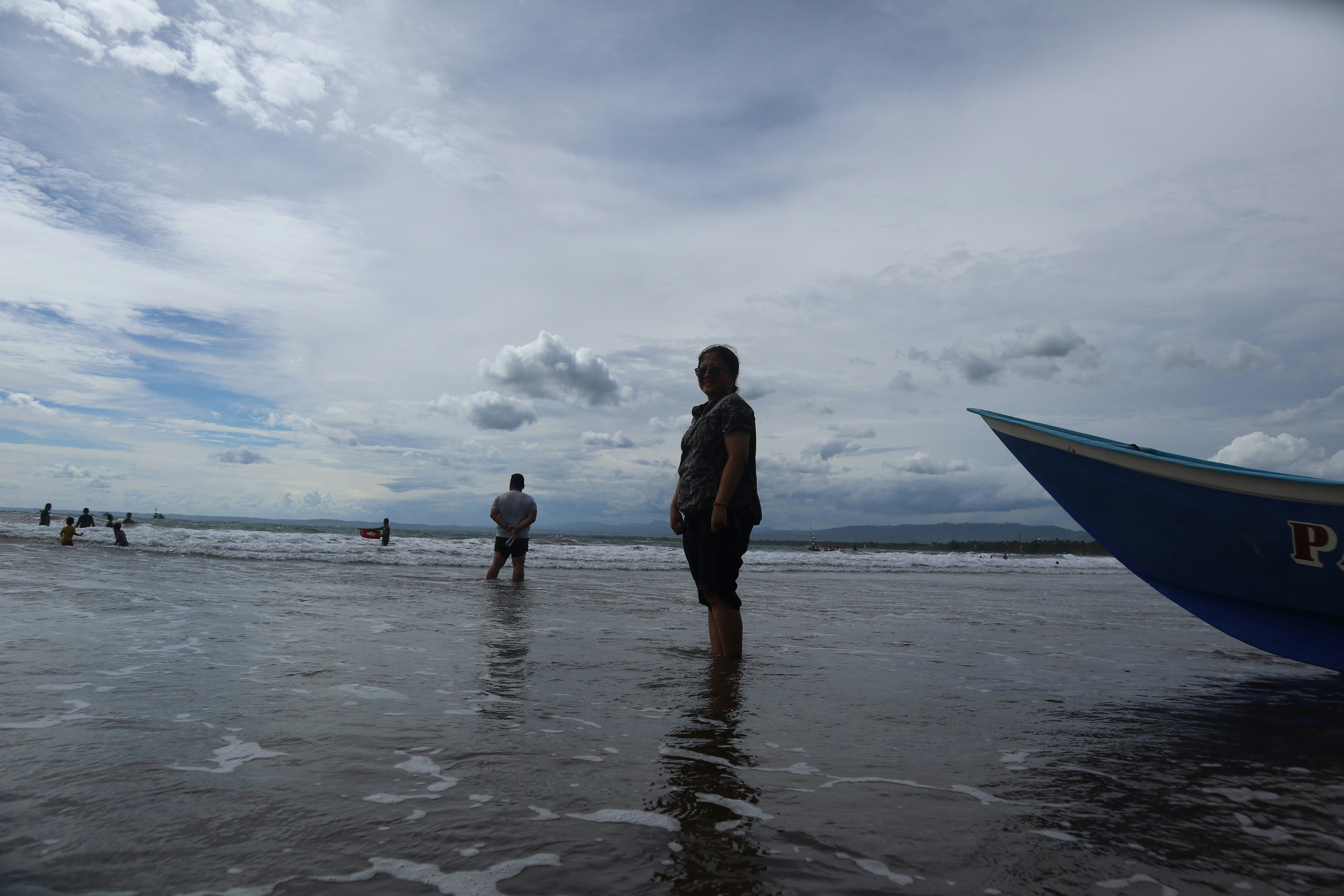 Un gruppo di persone in piedi in cima a una spiaggia accanto a una barca