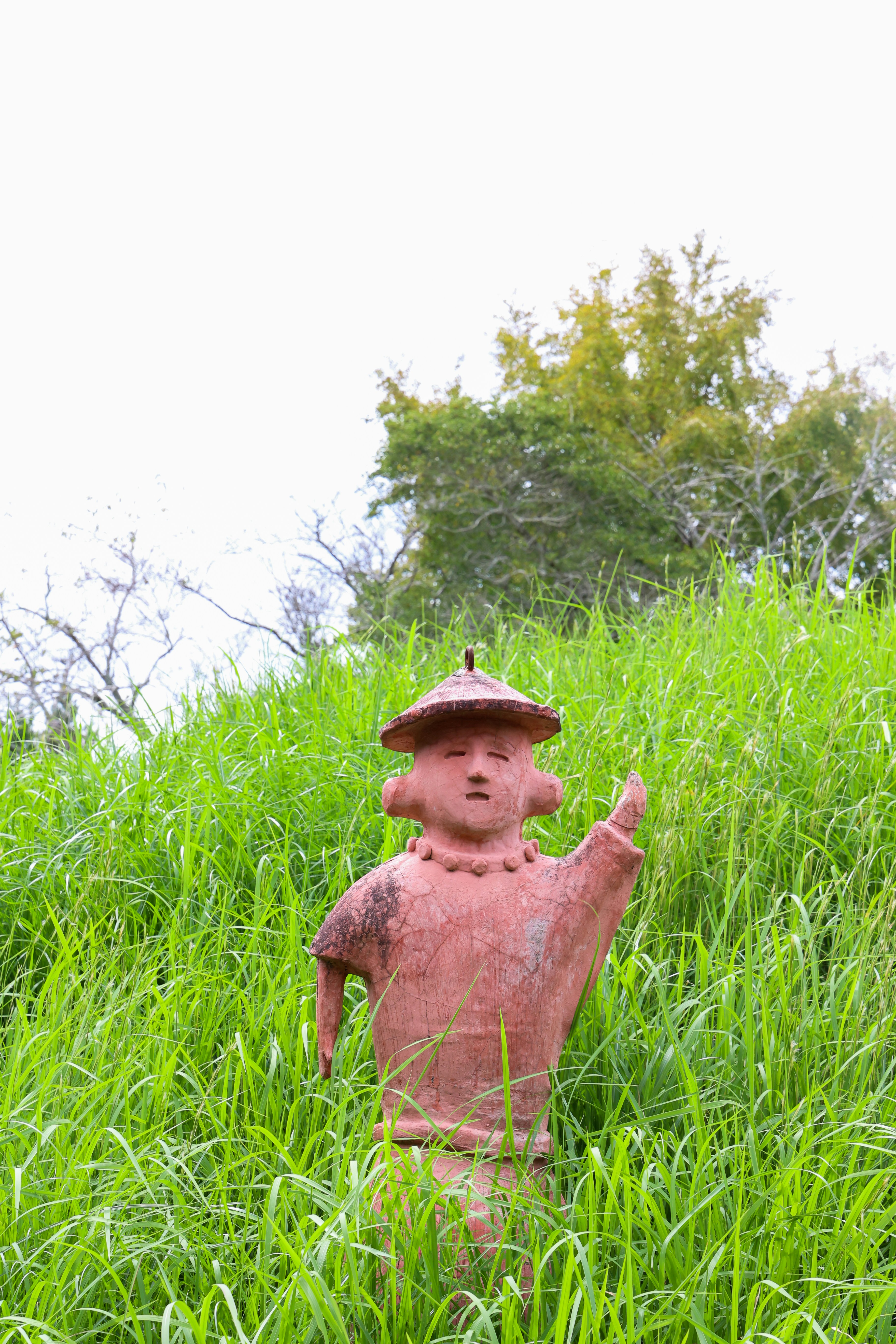 A statue of a boy in a field of tall grass
