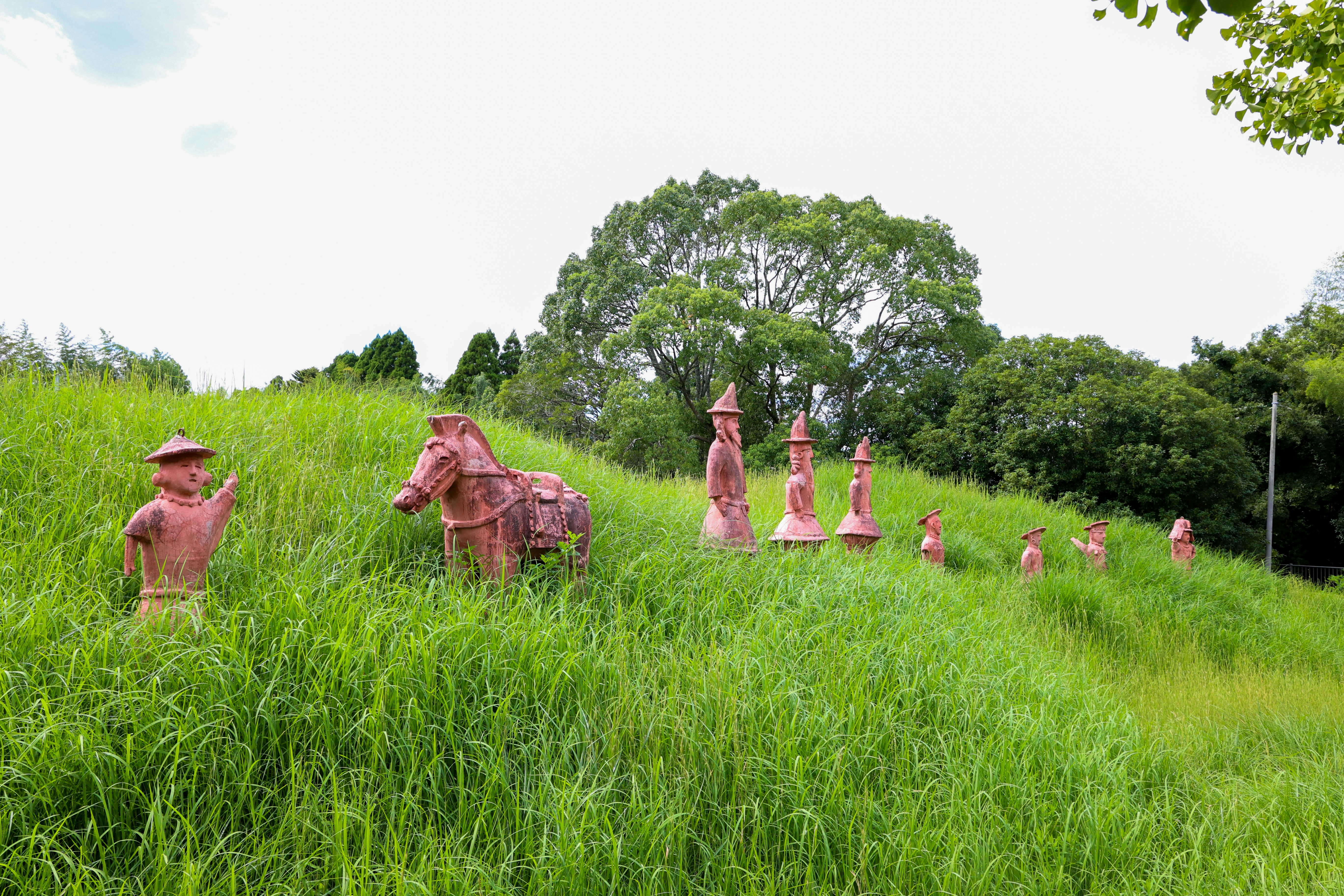 A group of statues sitting on top of a lush green hillside