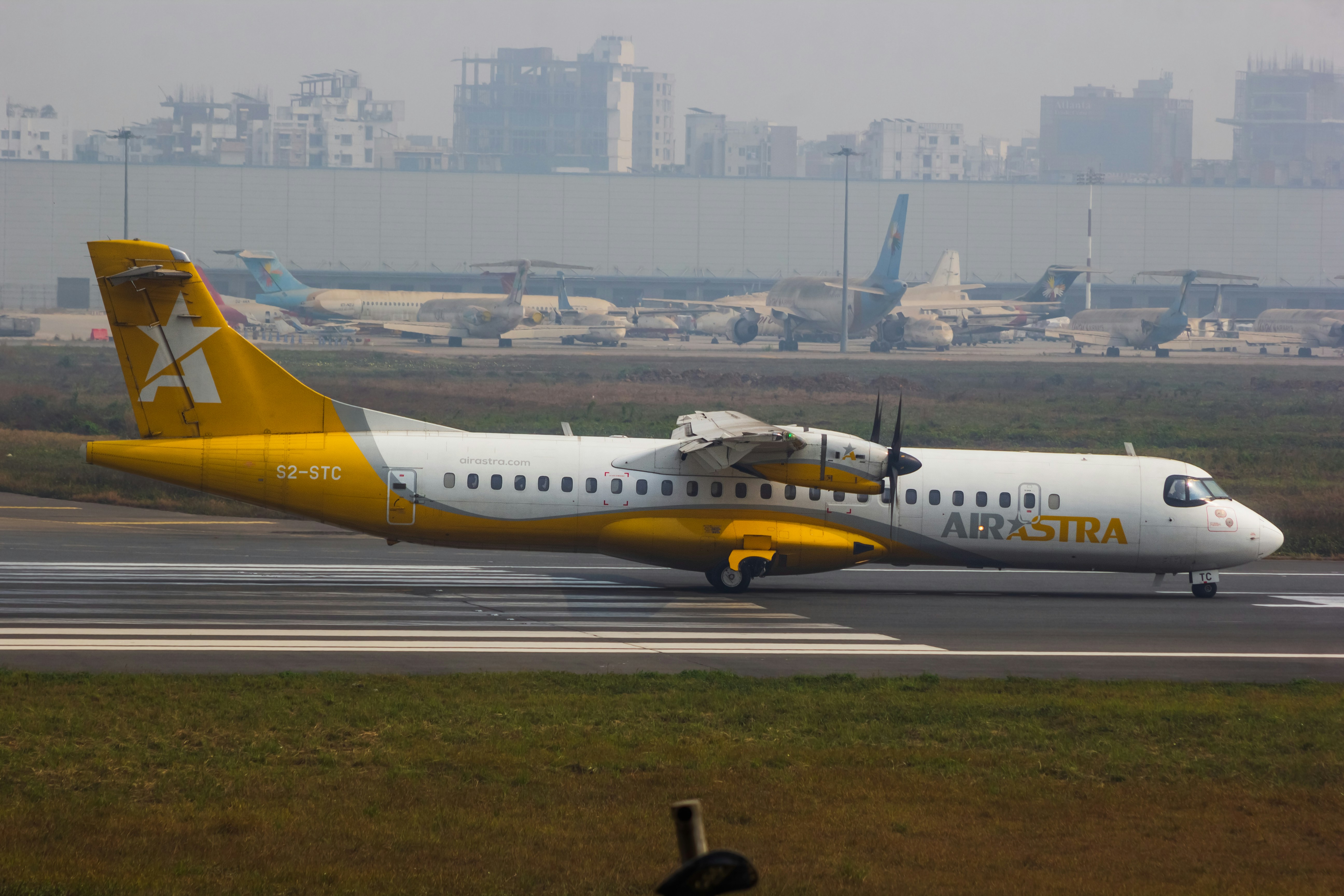 A yellow and white airplane is on the runway, AirAstra - ATR 72-600