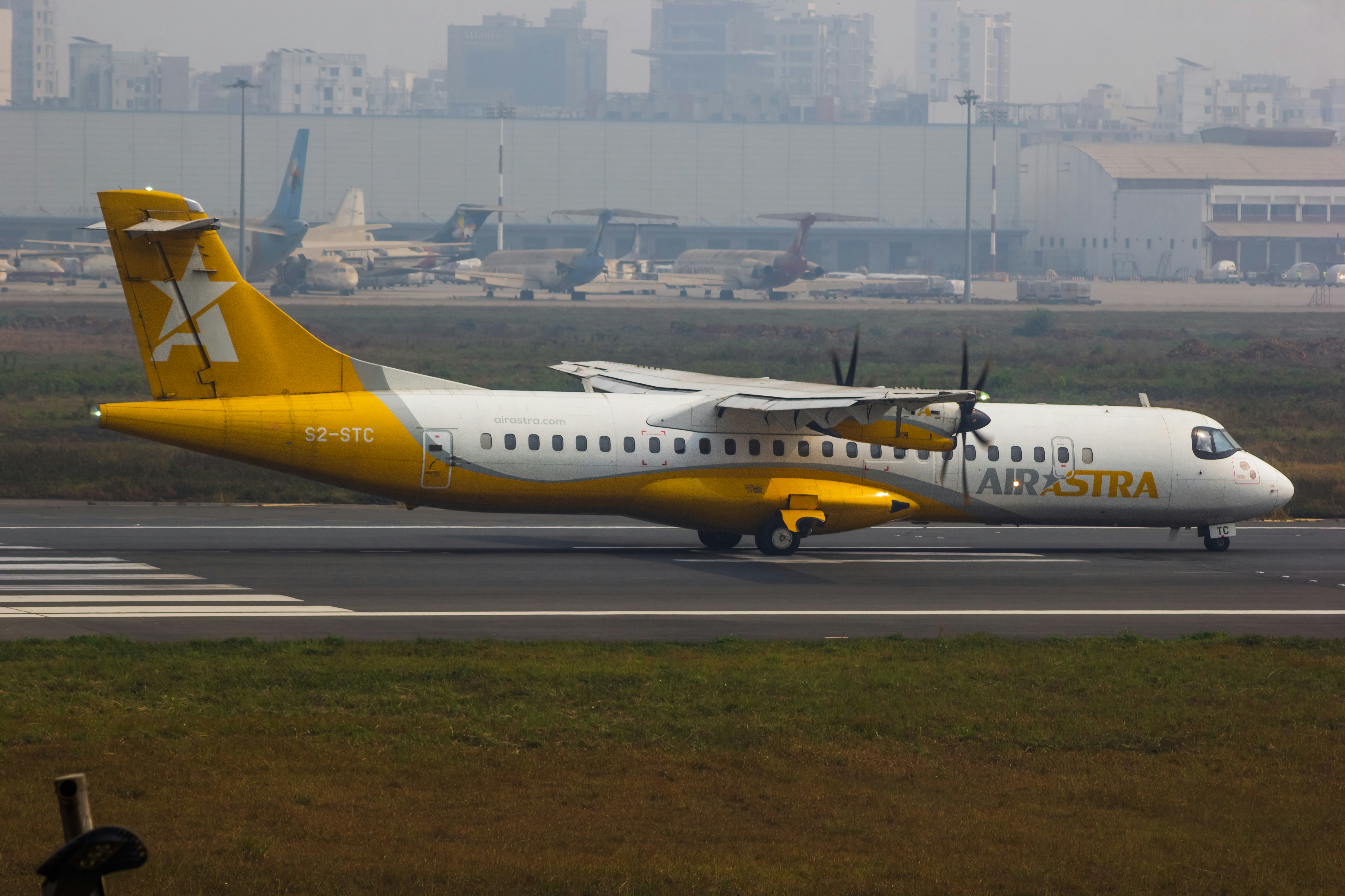 A yellow and white airplane is on the runway
