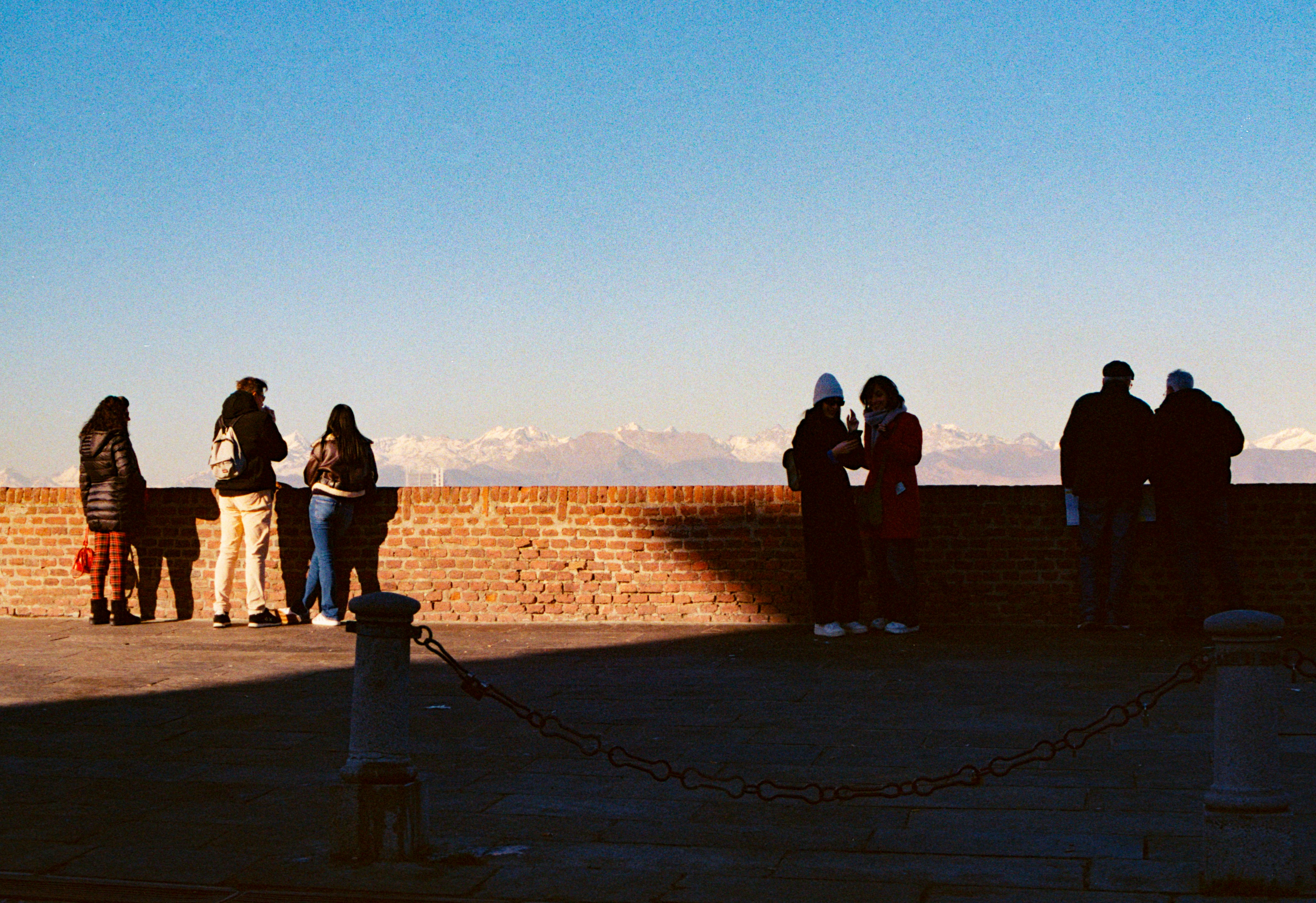A group of people standing on top of a brick wall