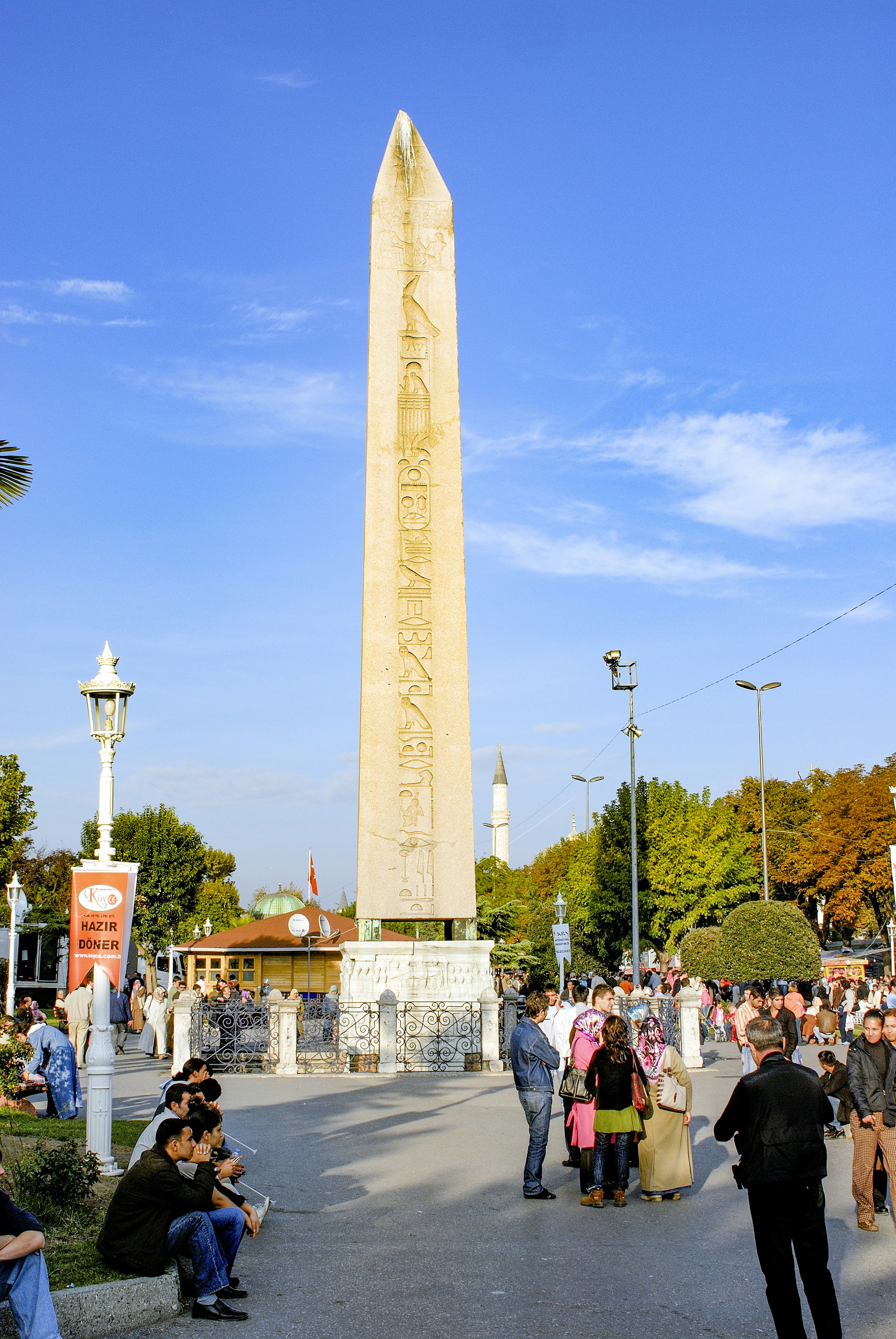Un grupo de personas de pie alrededor de un alto obelisco