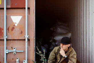A man sitting on the ground in front of a shipping container