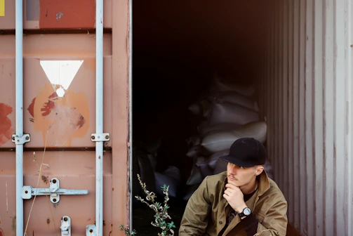 A man sitting on the ground in front of a shipping container