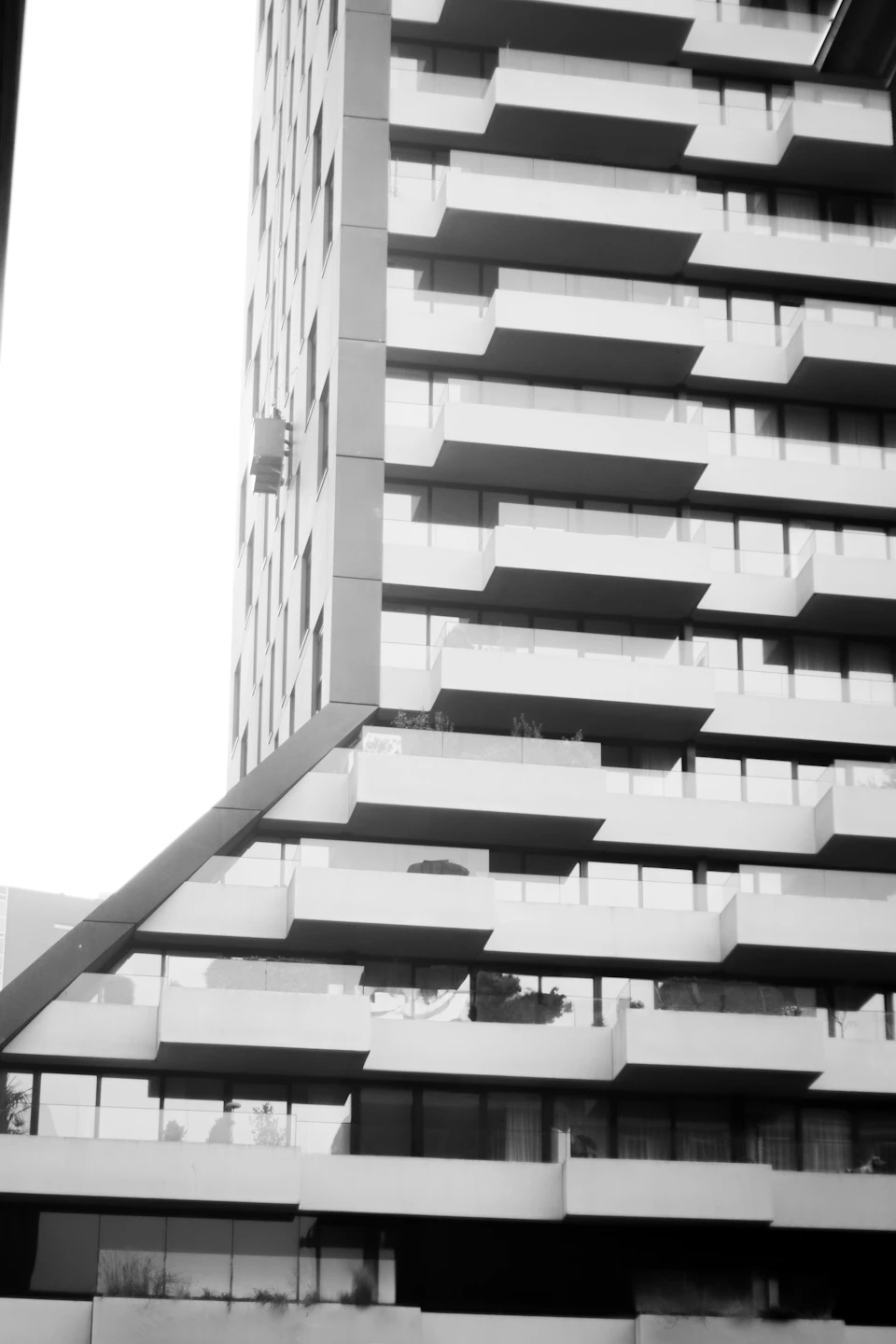Modern building with unique balconies on each floor viewed from directly below in black and