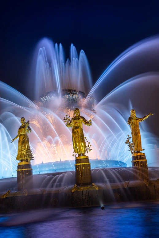 A water fountain with three golden statues in front of it