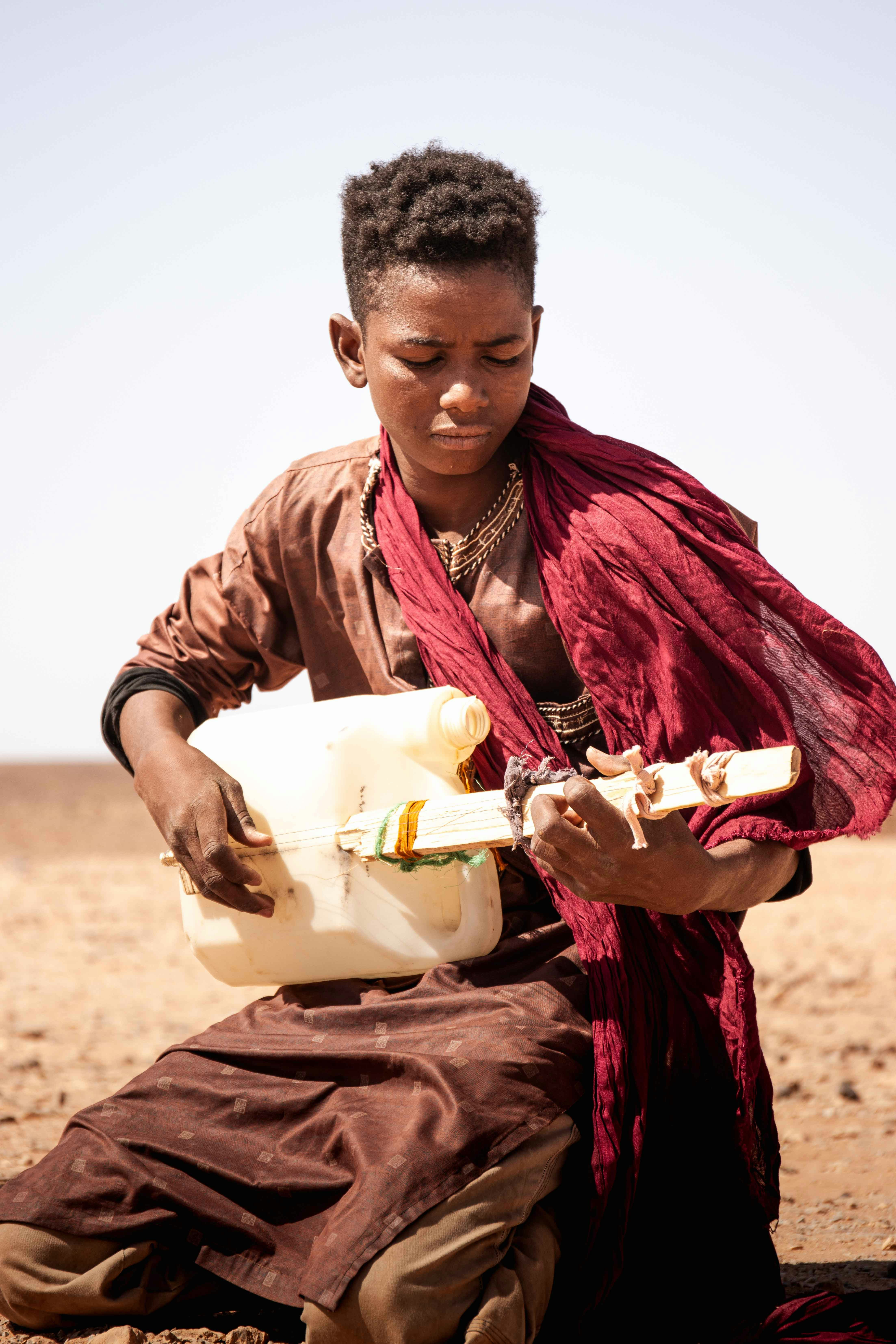 A woman sitting in the desert eating a sandwich