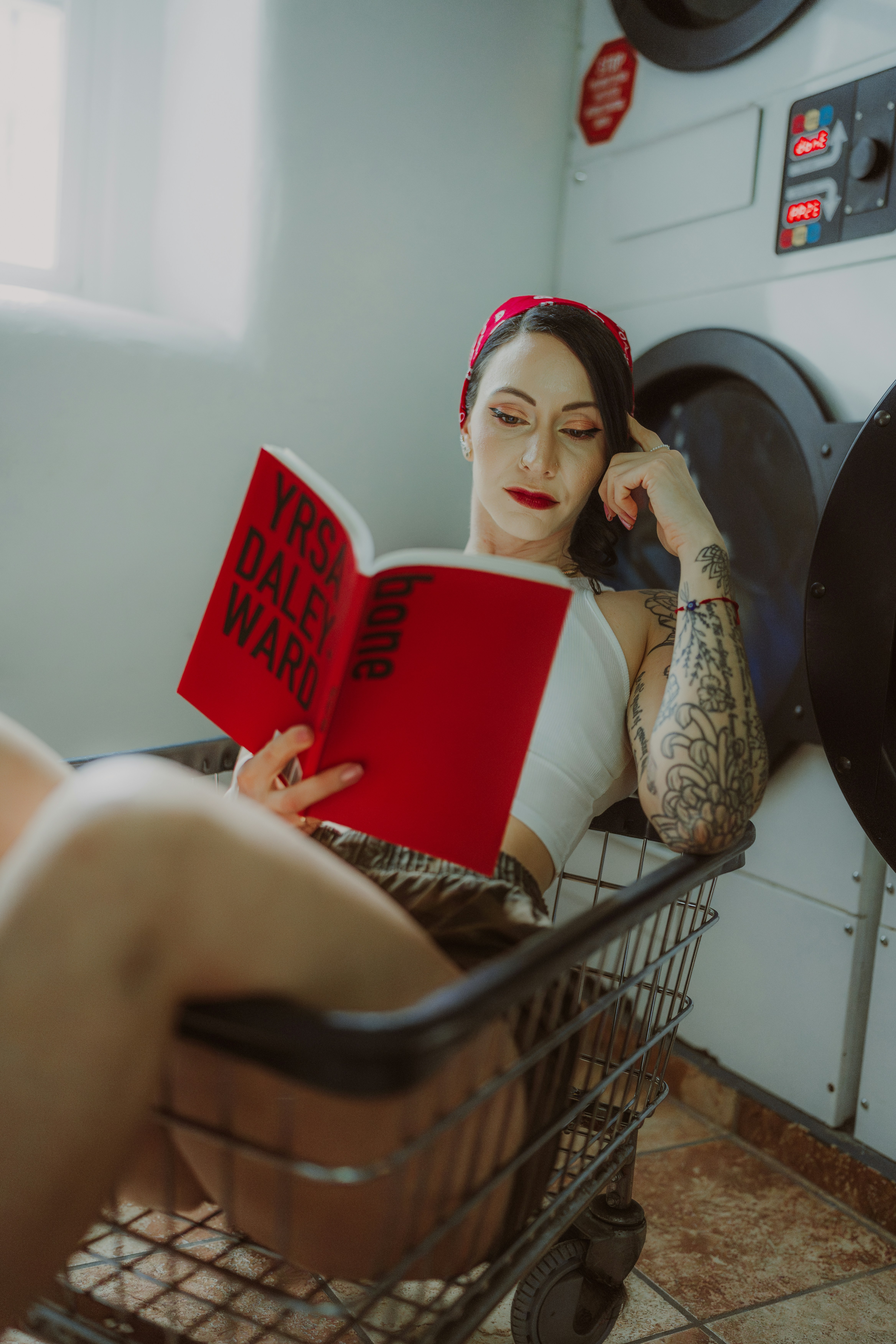 A woman sitting in a laundry room reading a book