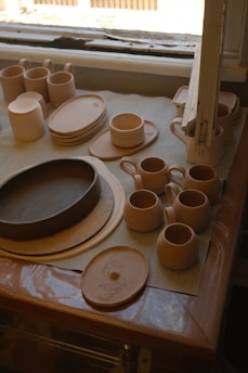 A table topped with plates and cups next to a window