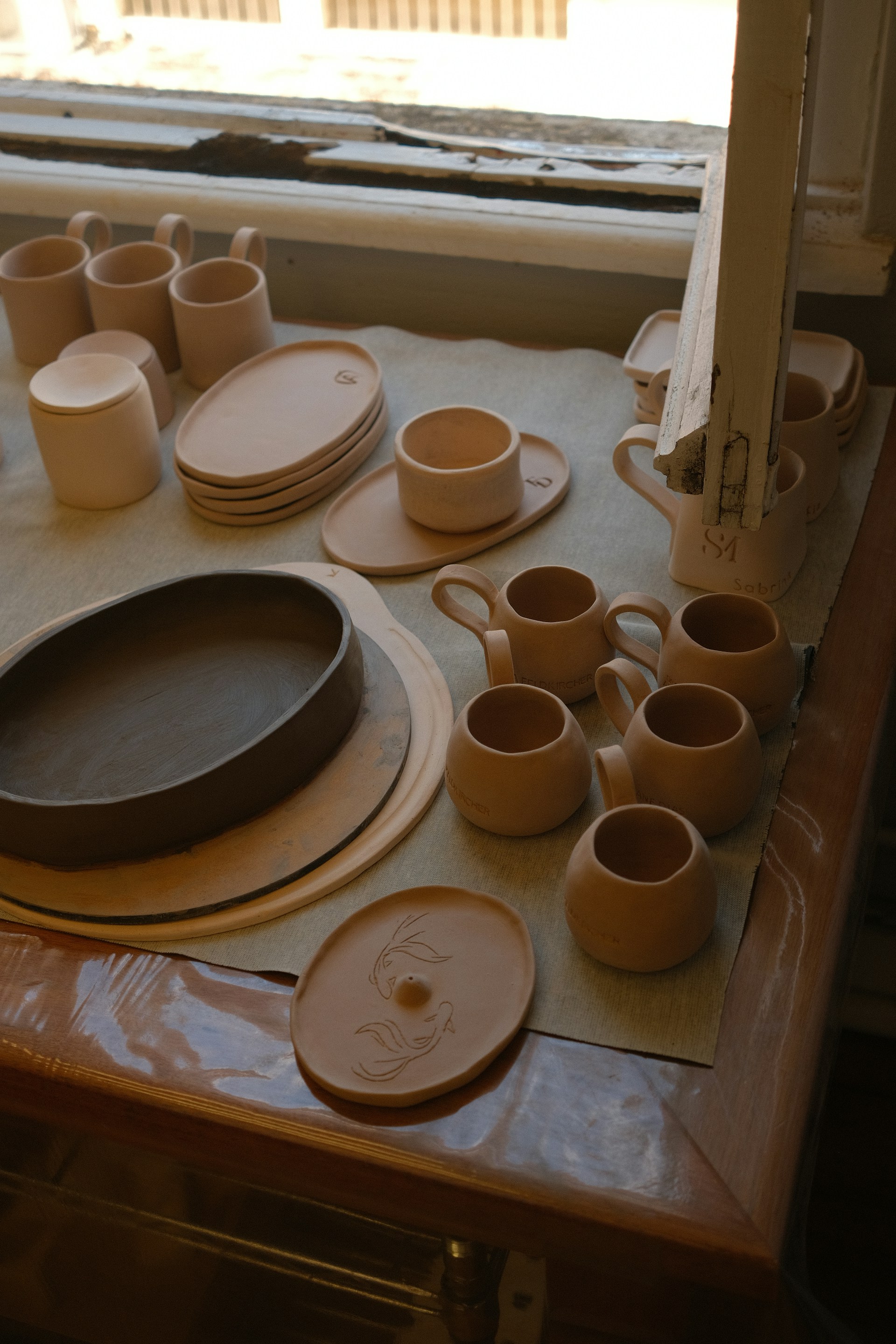 A table topped with plates and cups next to a window