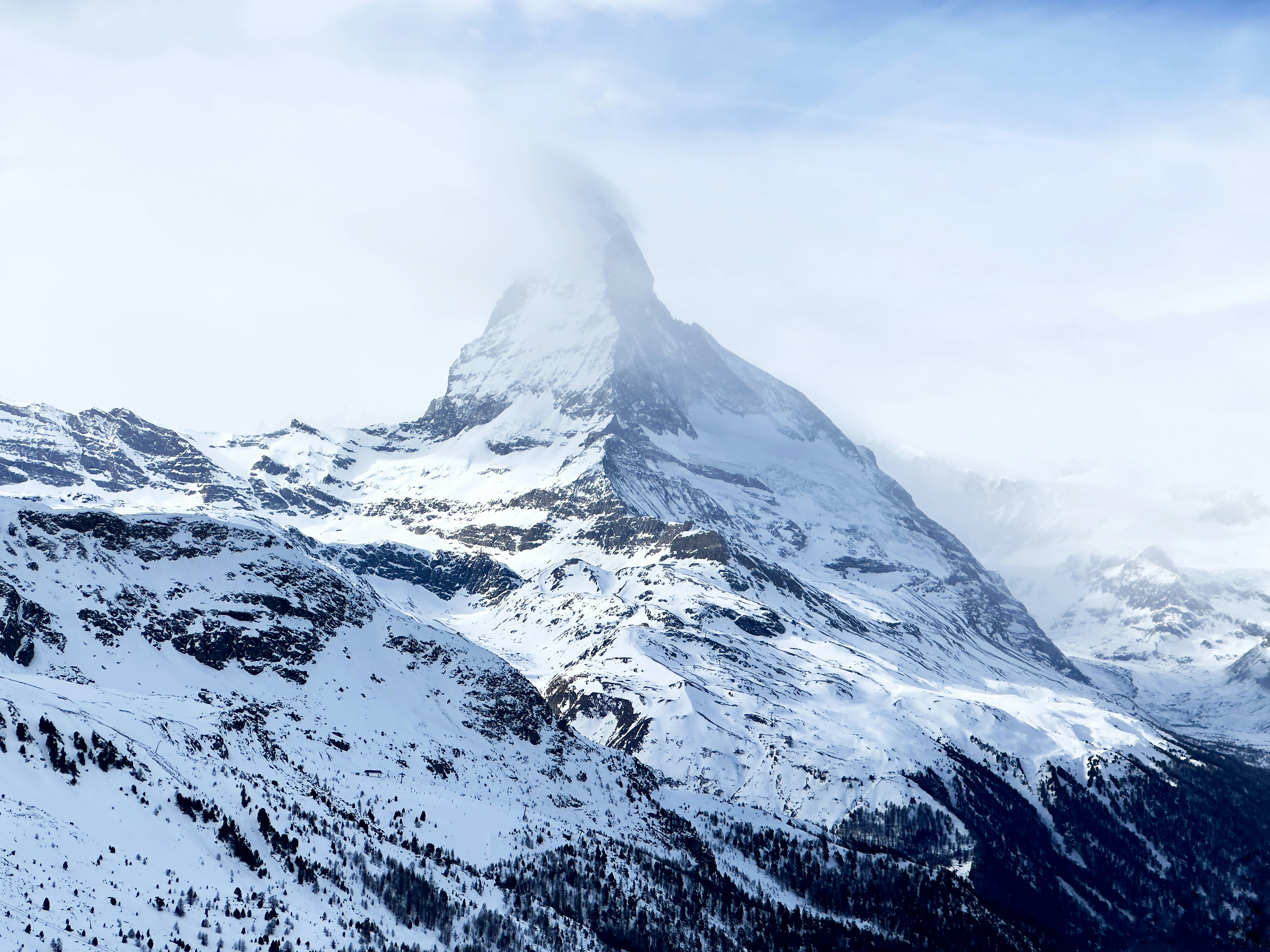 A mountain covered in snow with a cloud in the sky