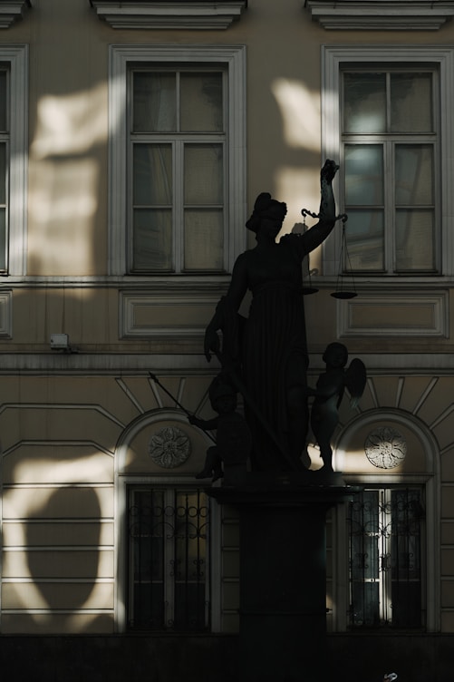 Uma estátua de uma mulher segurando uma balança, com dois querubins ao seu lado.