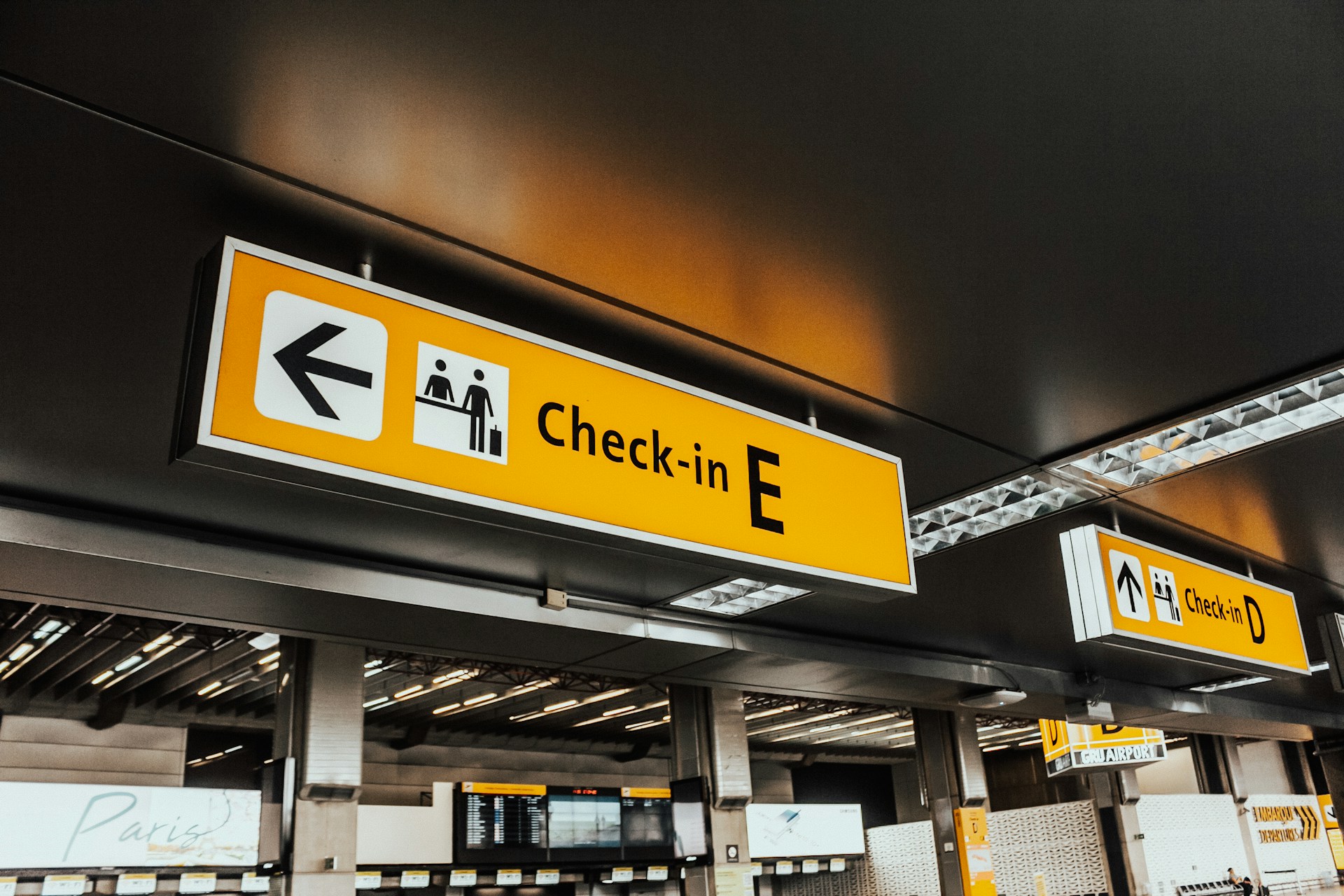 A yellow and white check in sign hanging from a ceiling