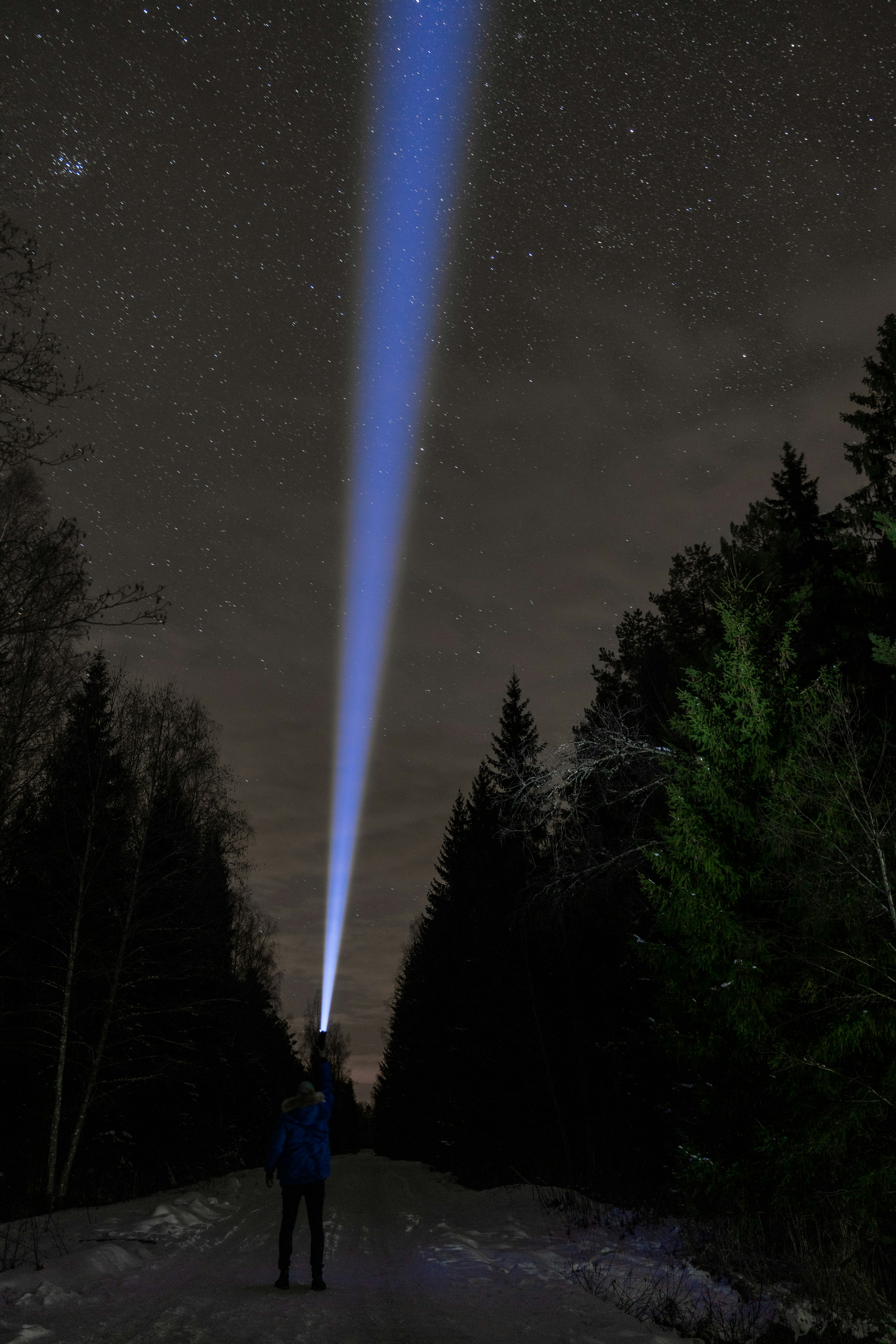 A person standing on a snow covered road under a sky filled with stars