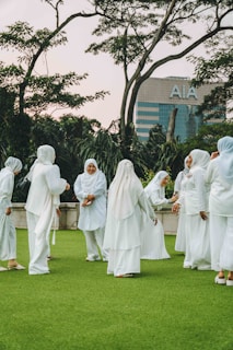 A group of women dressed in white standing on a lush green field