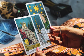 A person holding two tarot cards in their hands