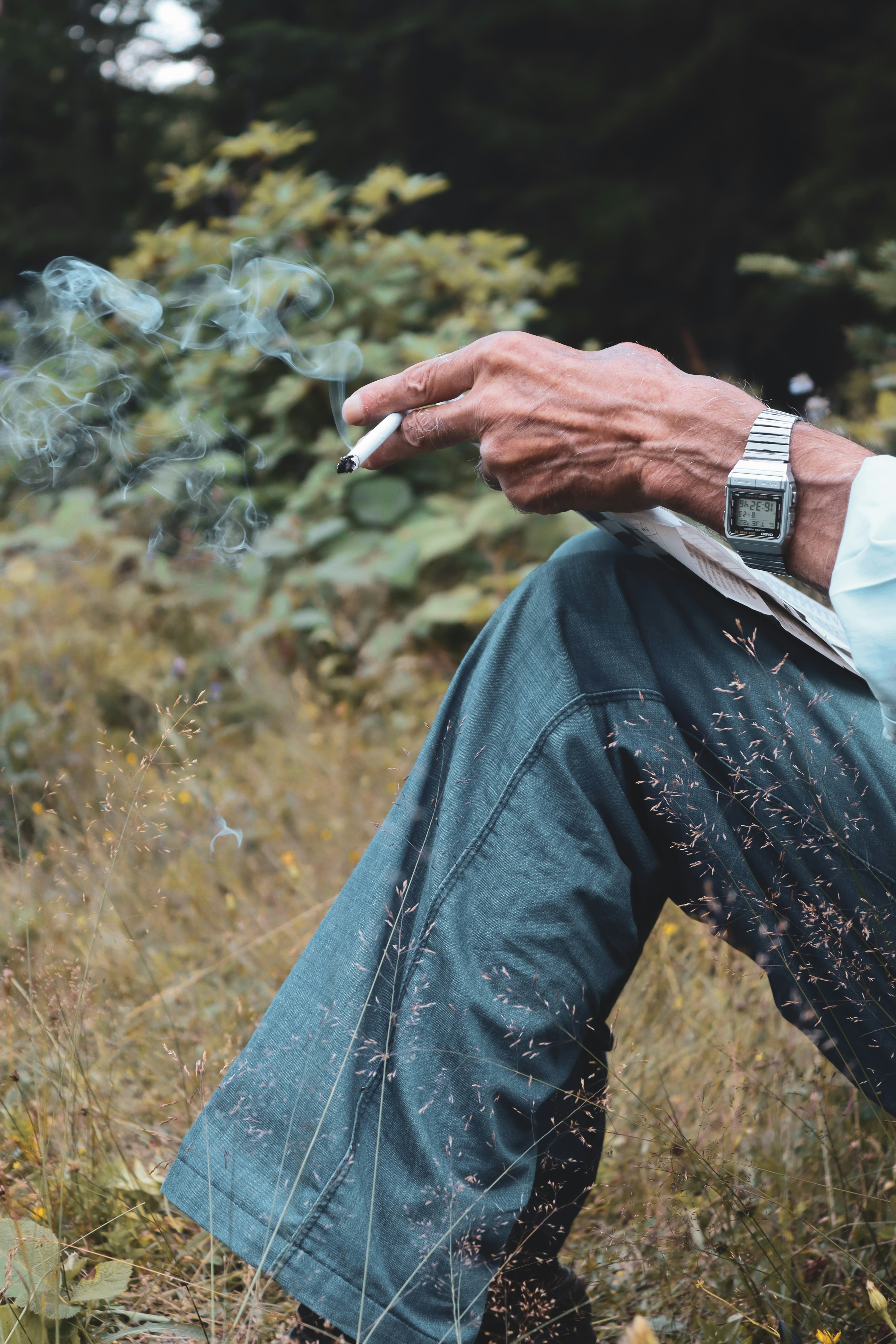 um, homem, sentando, em, um, campo, com, um, cigarro, em, seu, mão