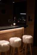 Three white stools in front of a bar