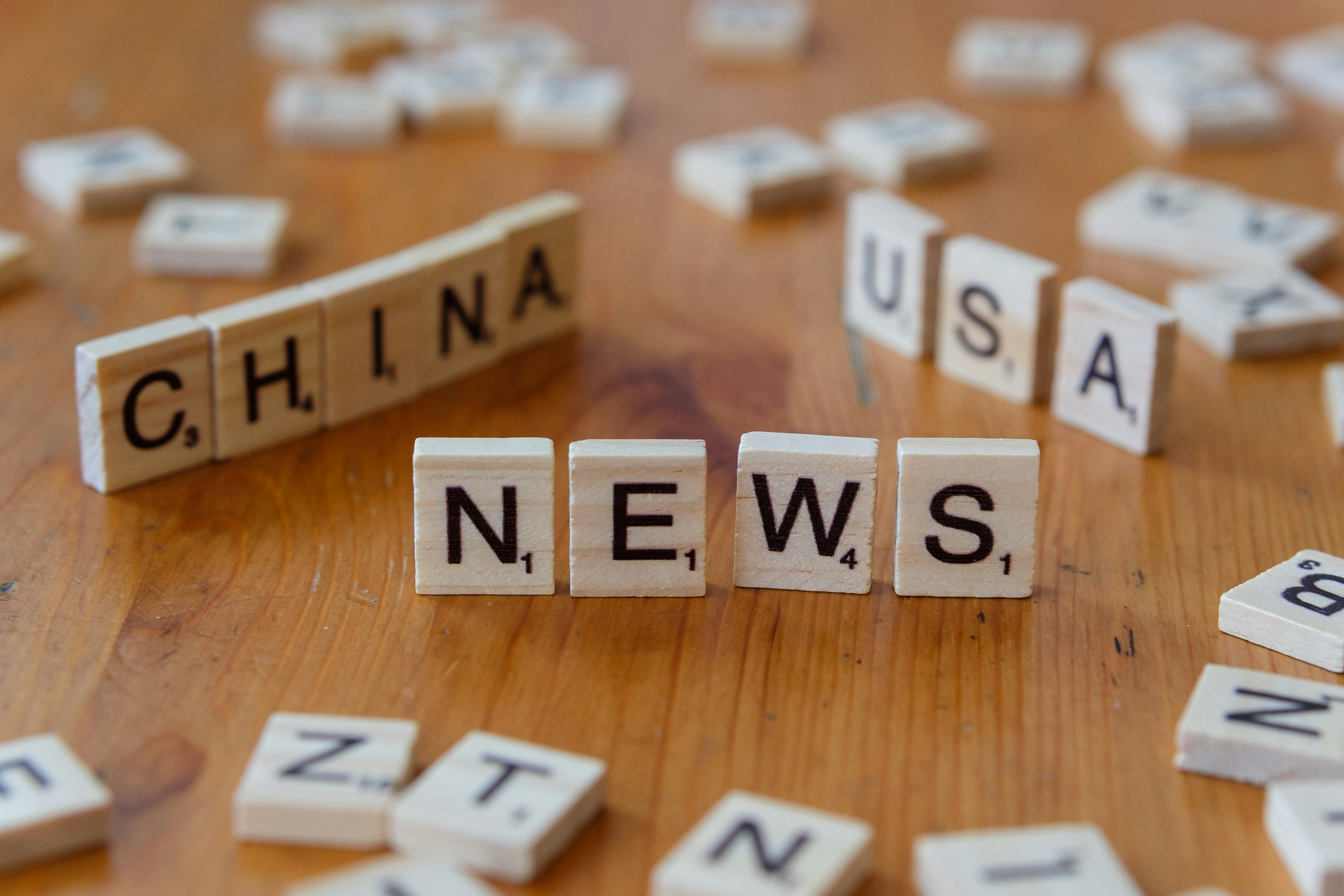 A wooden table topped with scrabble tiles spelling china news