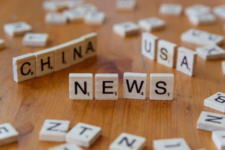 A wooden table topped with scrabble tiles spelling china news