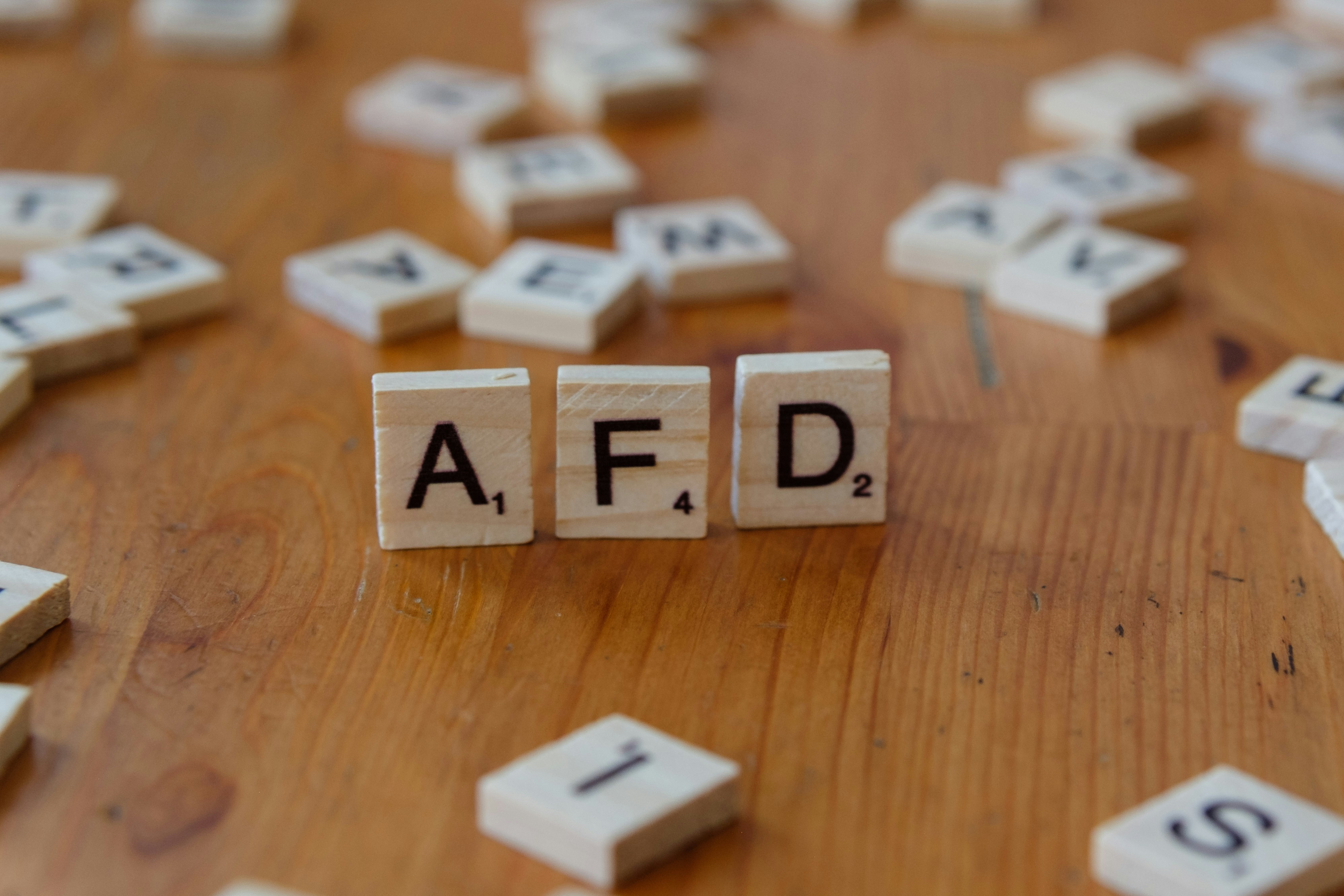 A wooden table topped with scrabble tiles spelling the word afd