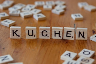 A wooden table topped with scrabble tiles that spell out the word kuchen