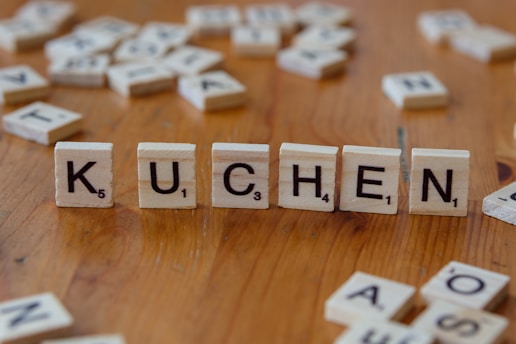 A wooden table topped with scrabble tiles that spell out the word kuchen