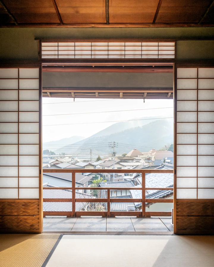 障子を開けた窓の向こうに広がる町並みと山