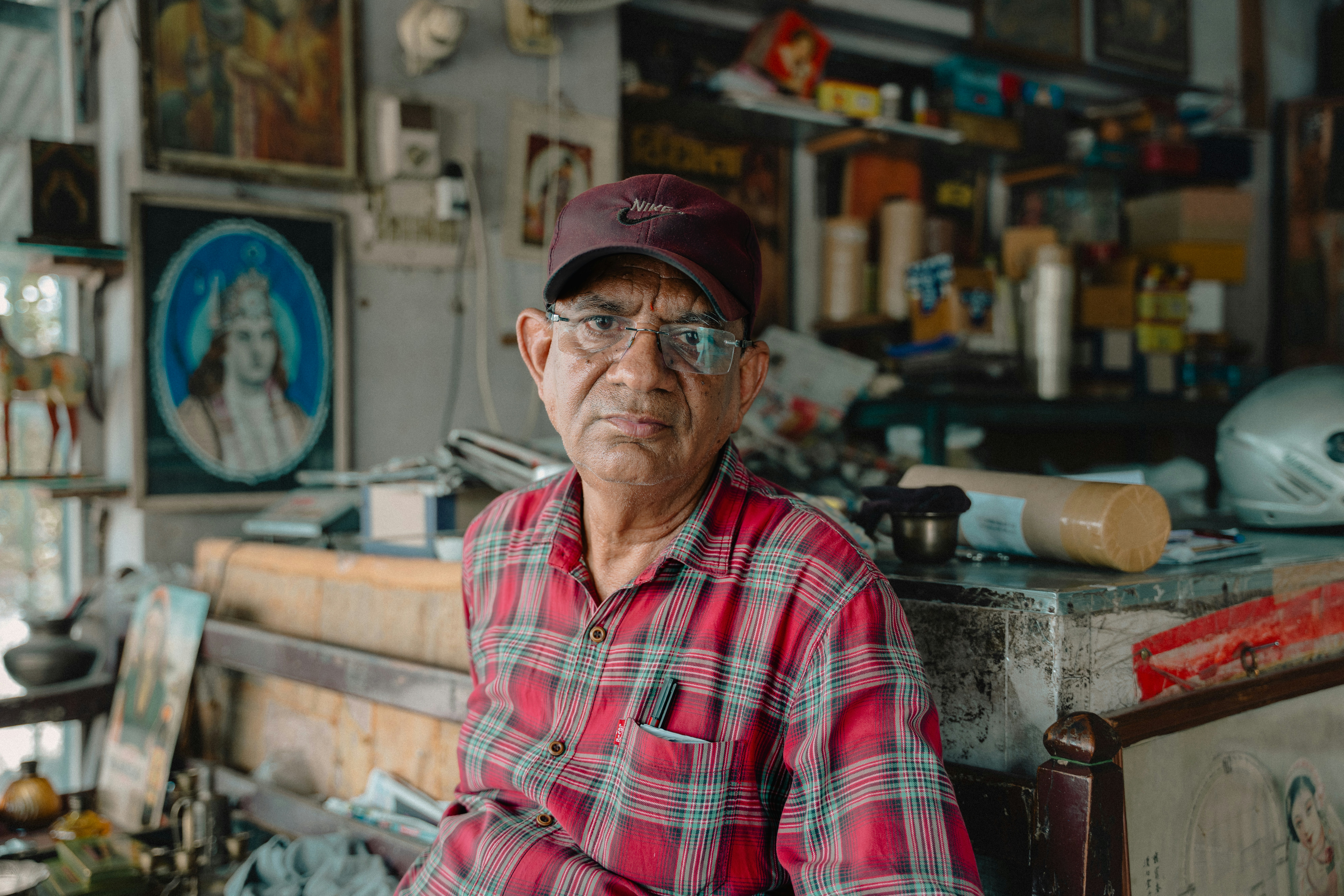 A man in a red and black checkered shirt sitting in a room filled with