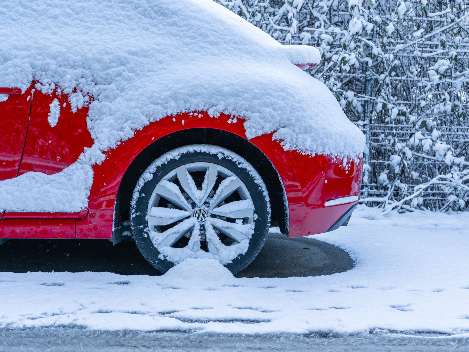 A red car covered in snow on a street