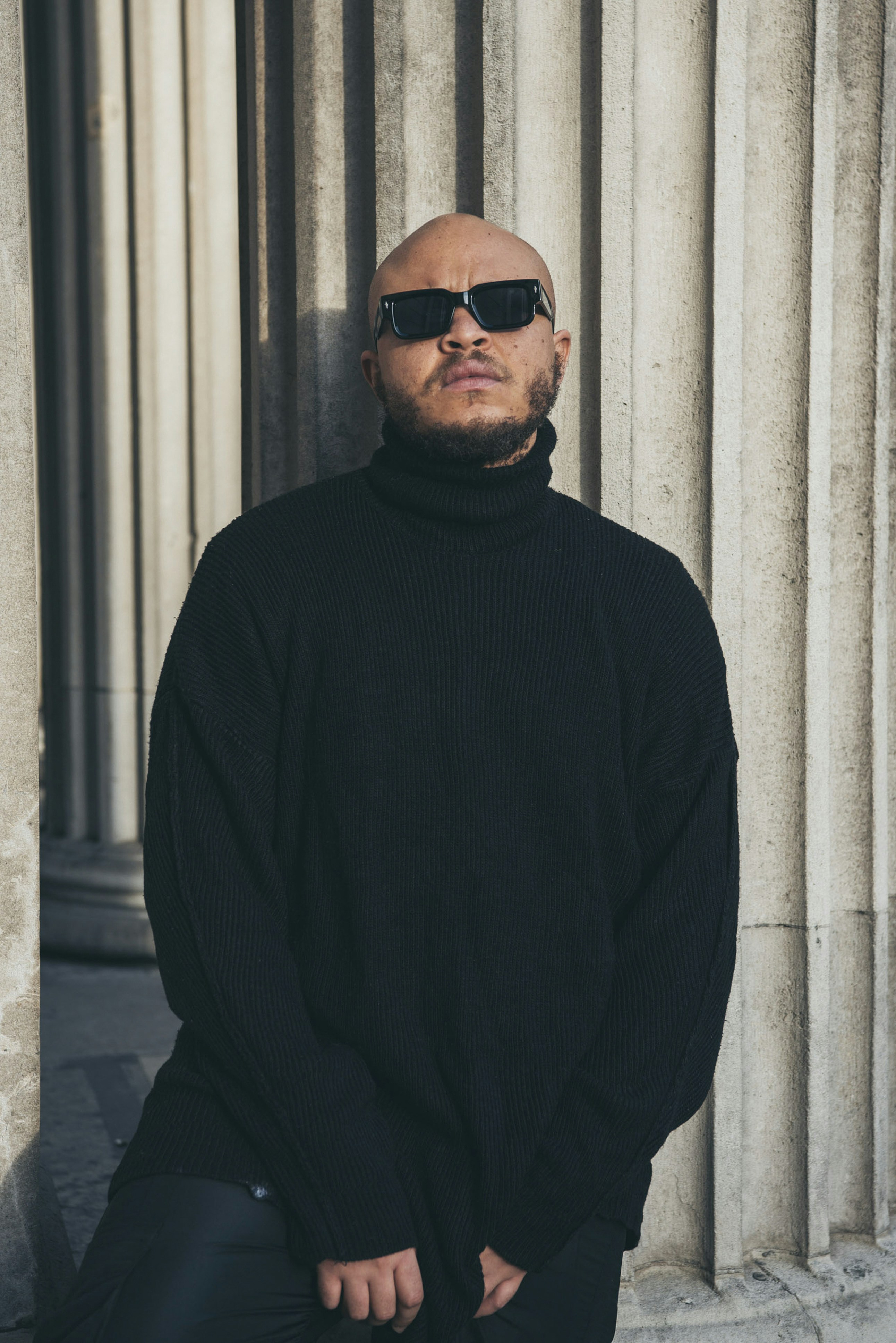 A man in a black turtle neck sweater and black pants