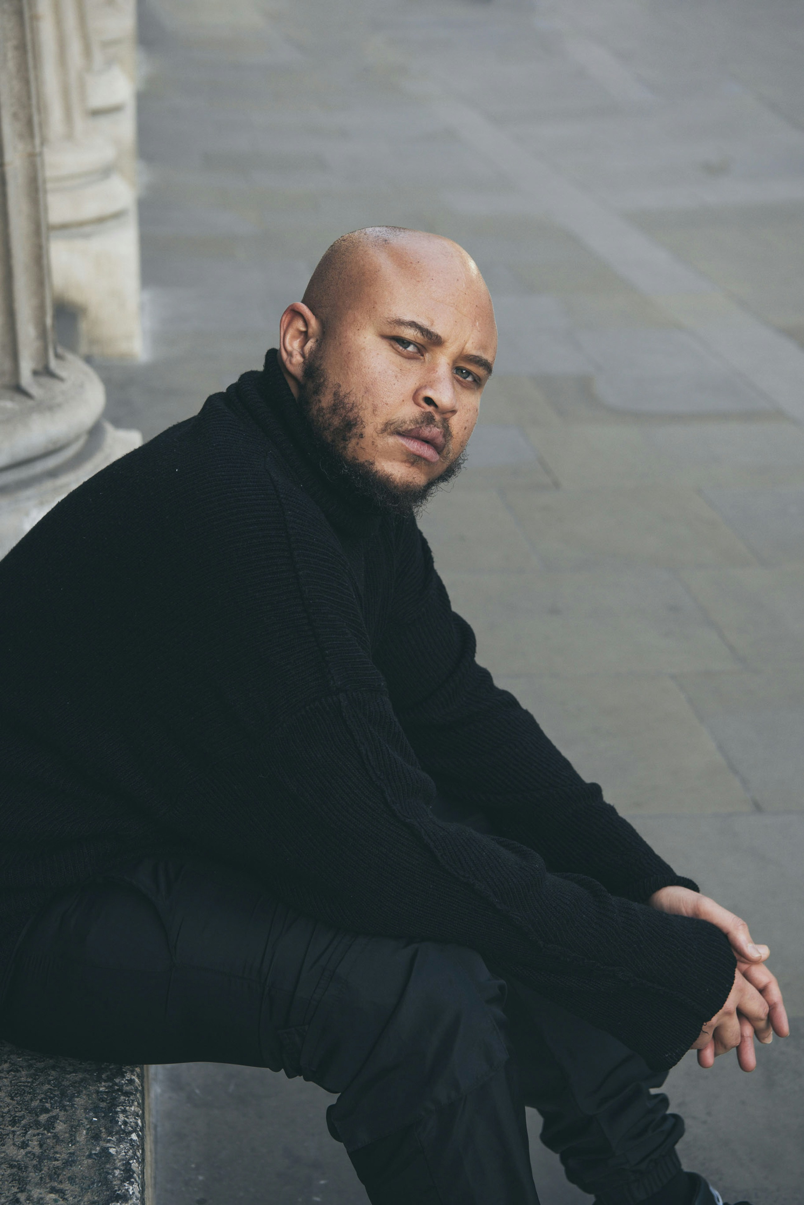 A bald man sitting on a stone bench