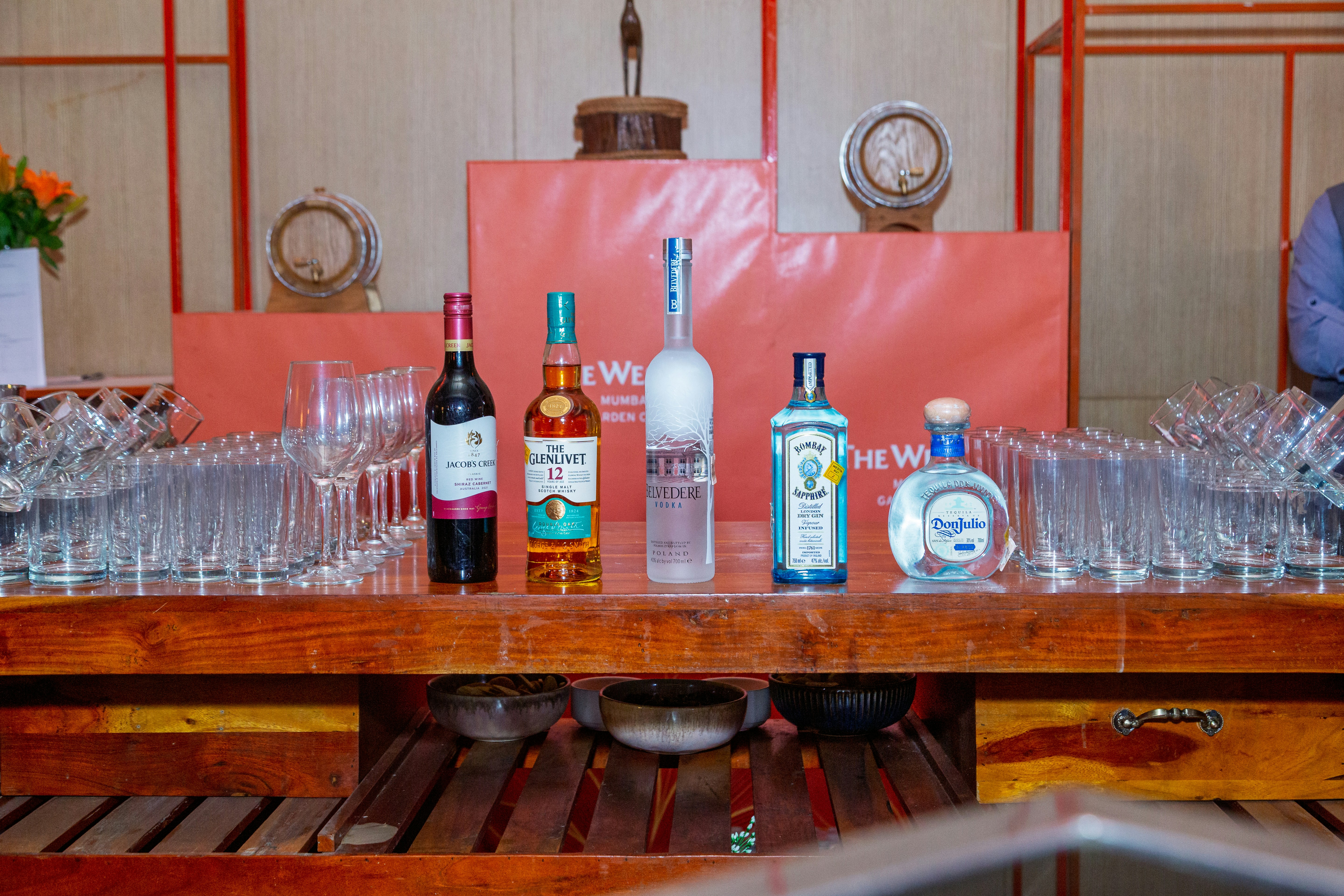 A wooden table topped with lots of bottles and glasses