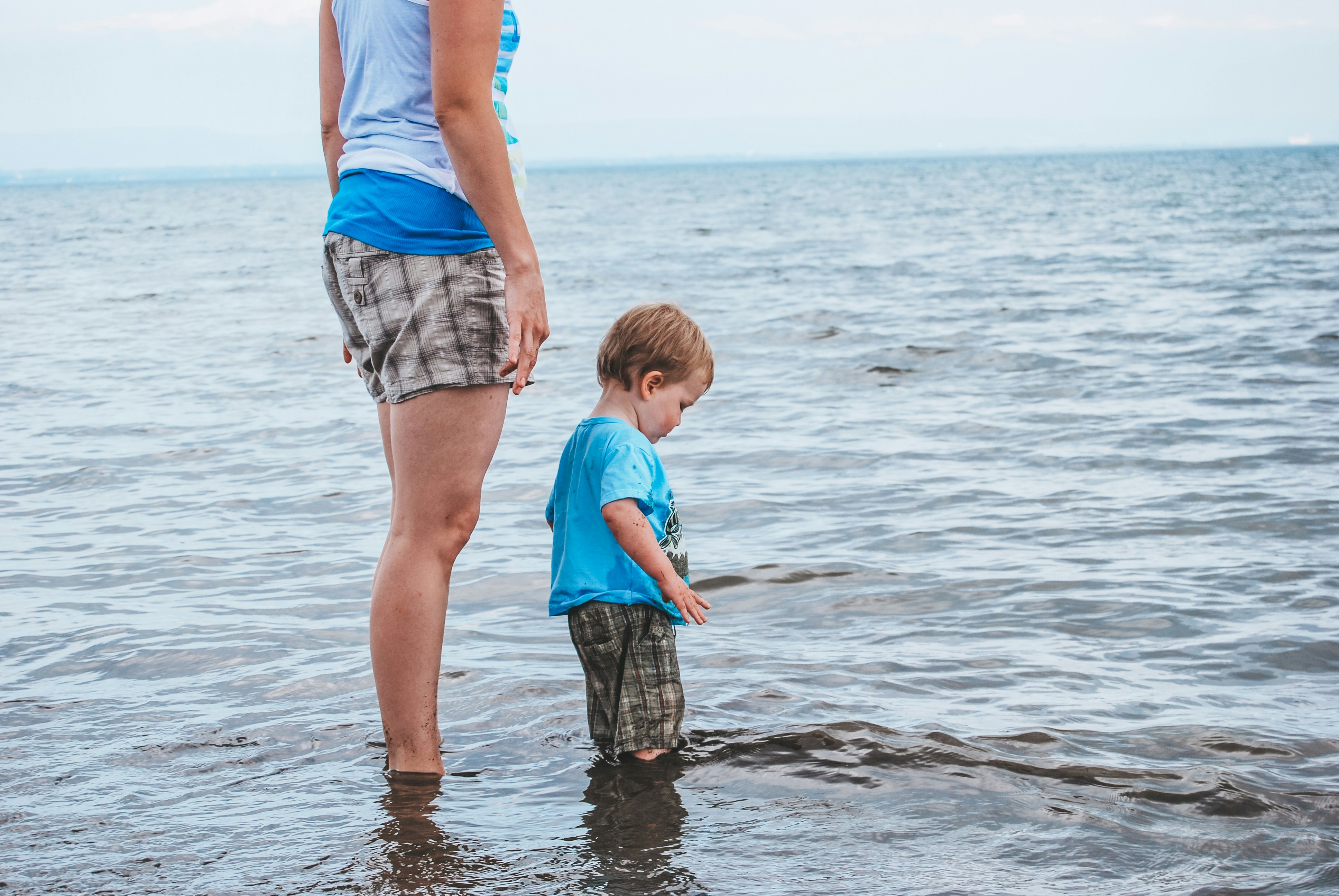 A woman standing next to a little boy on top of a beach