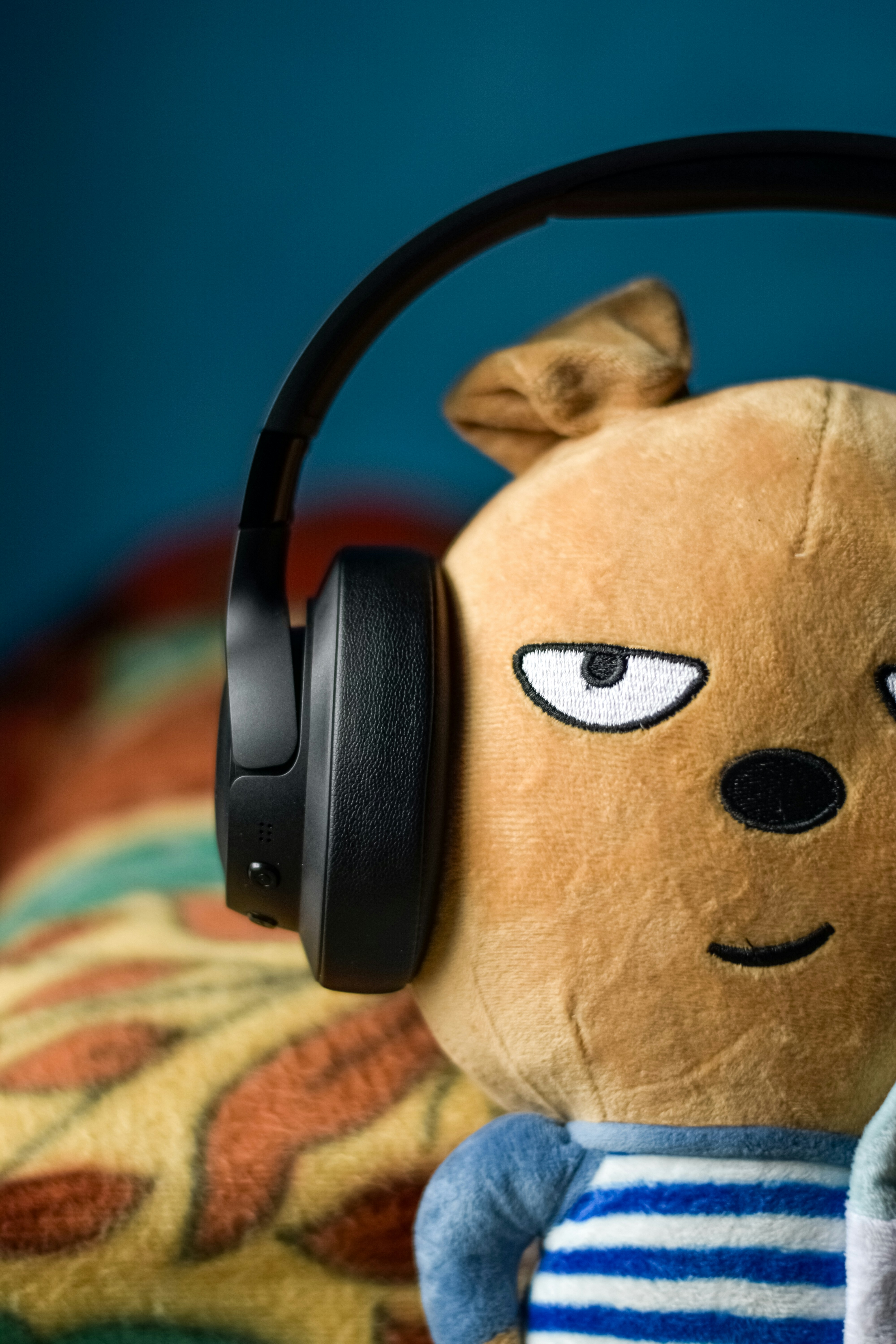 A stuffed animal wearing headphones on top of a bed