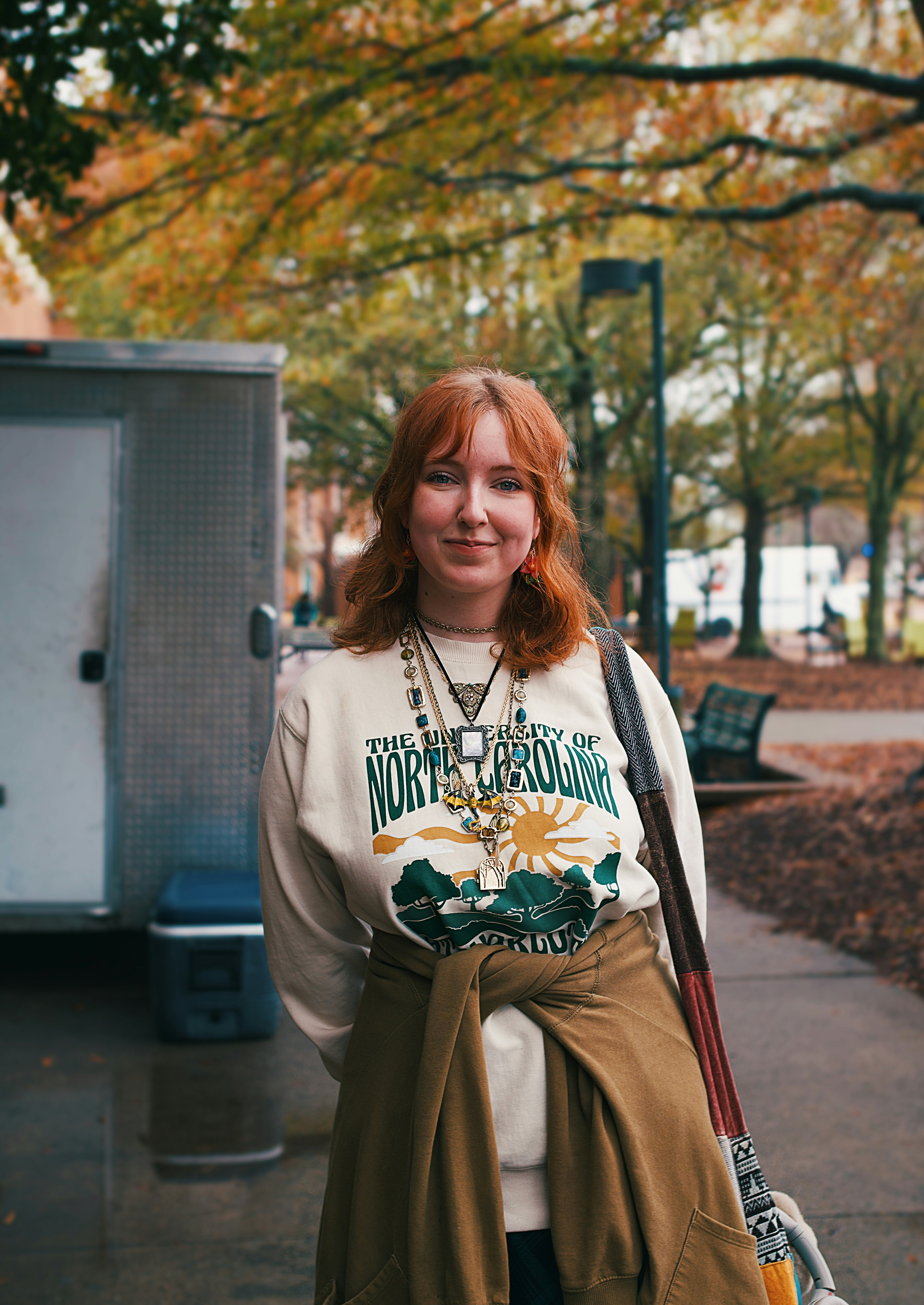 A woman standing on a sidewalk holding a skateboard