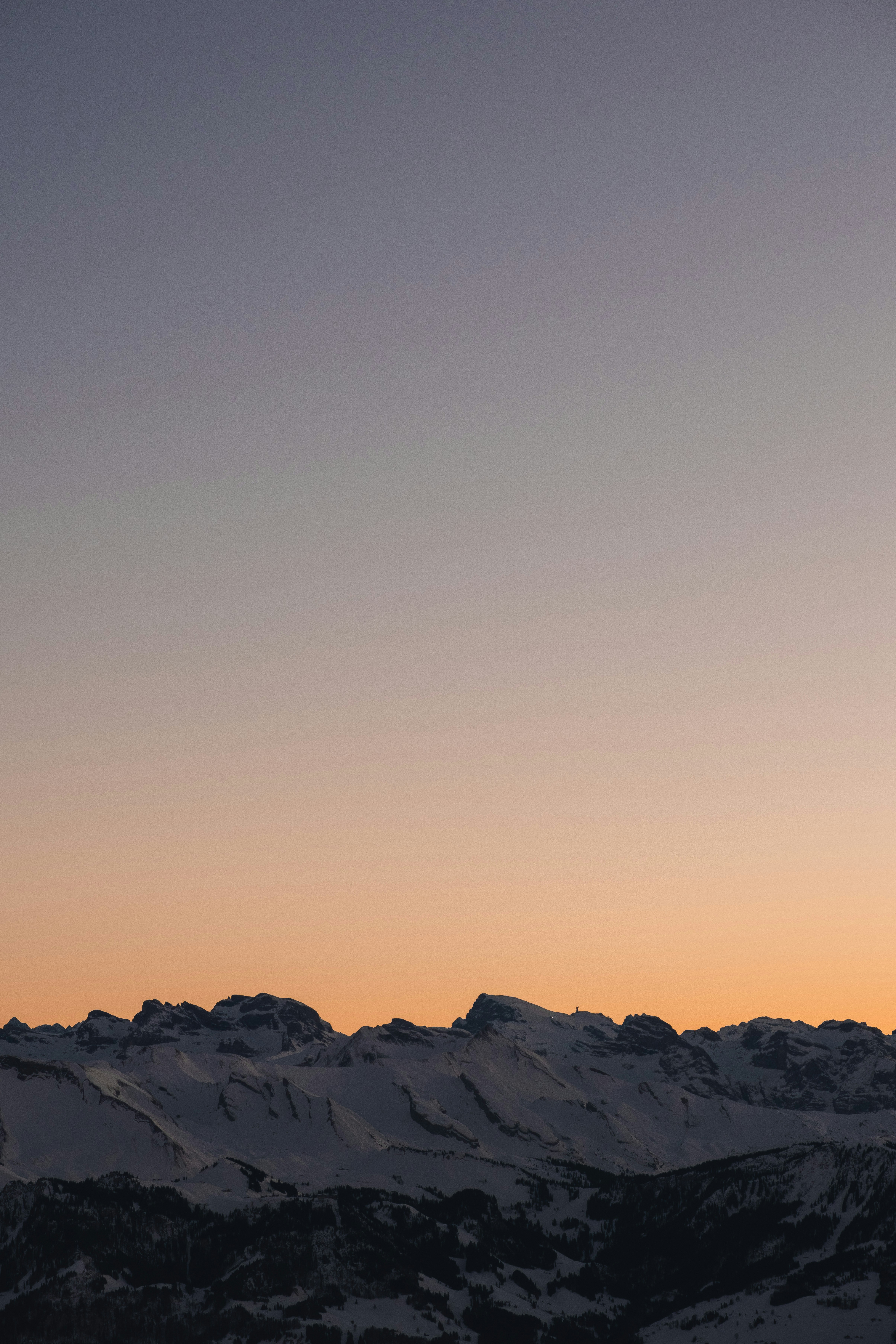 A plane flying over a mountain range at sunset