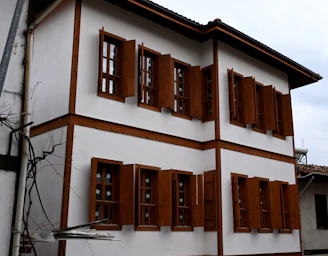 A white and brown house with wooden shutters