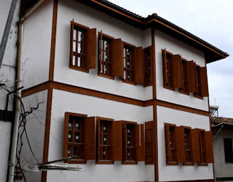 A white and brown house with wooden shutters