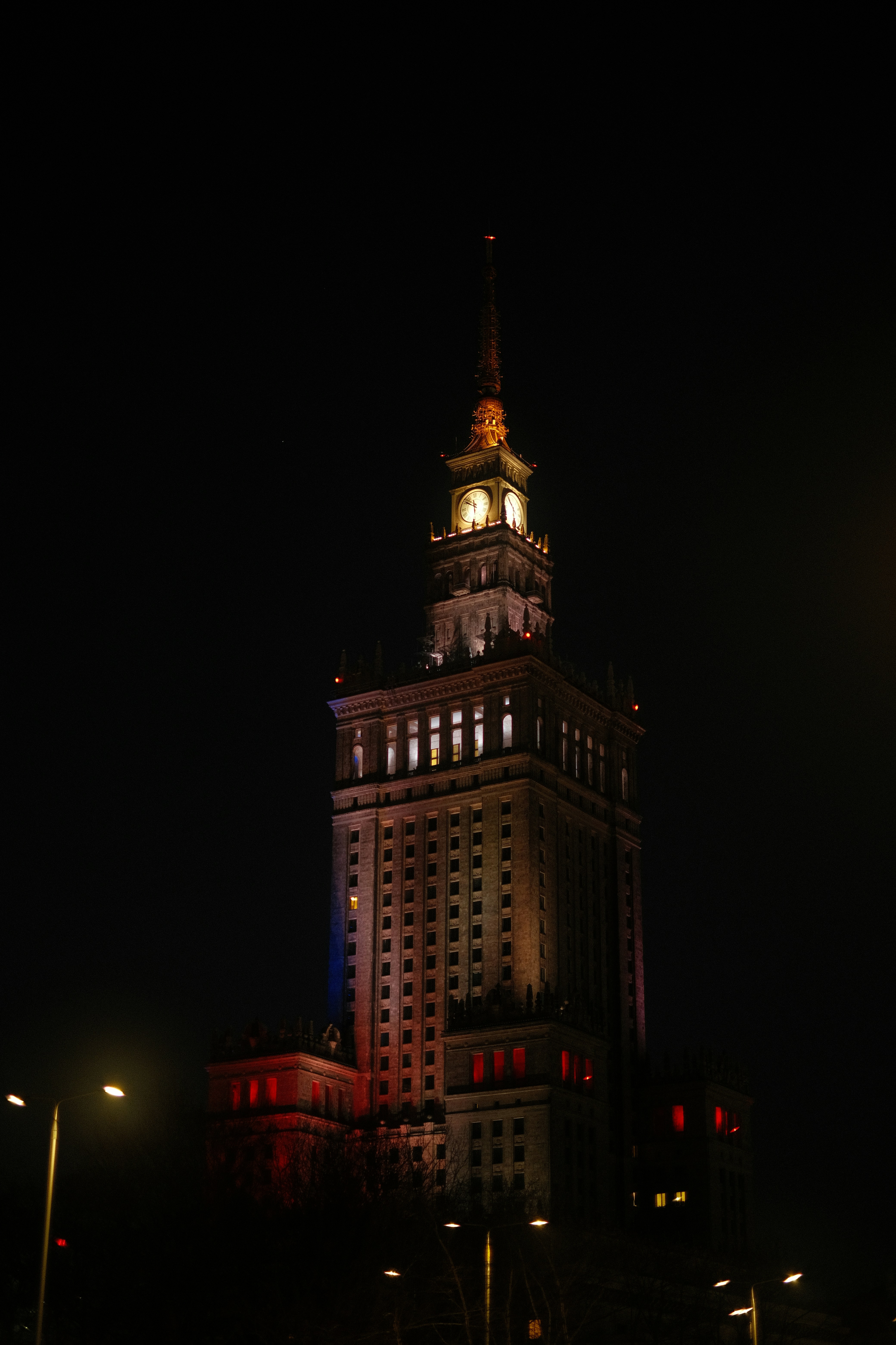 A tall building with a clock tower lit up at night