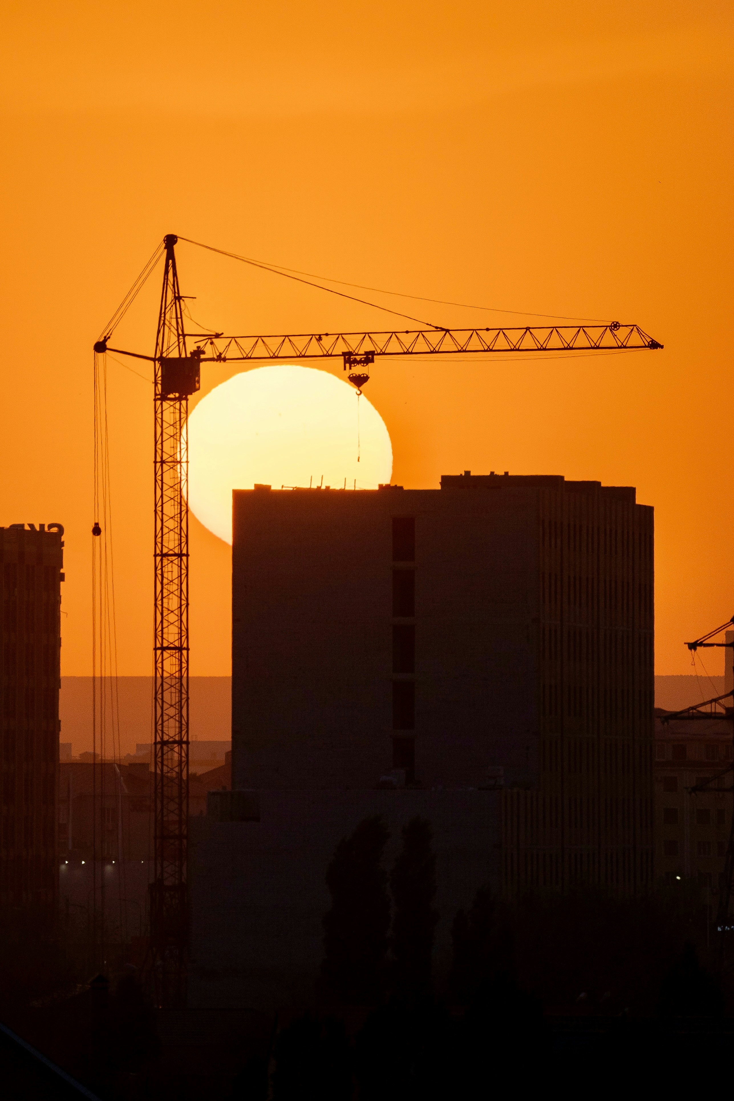 The sun is setting behind a construction site