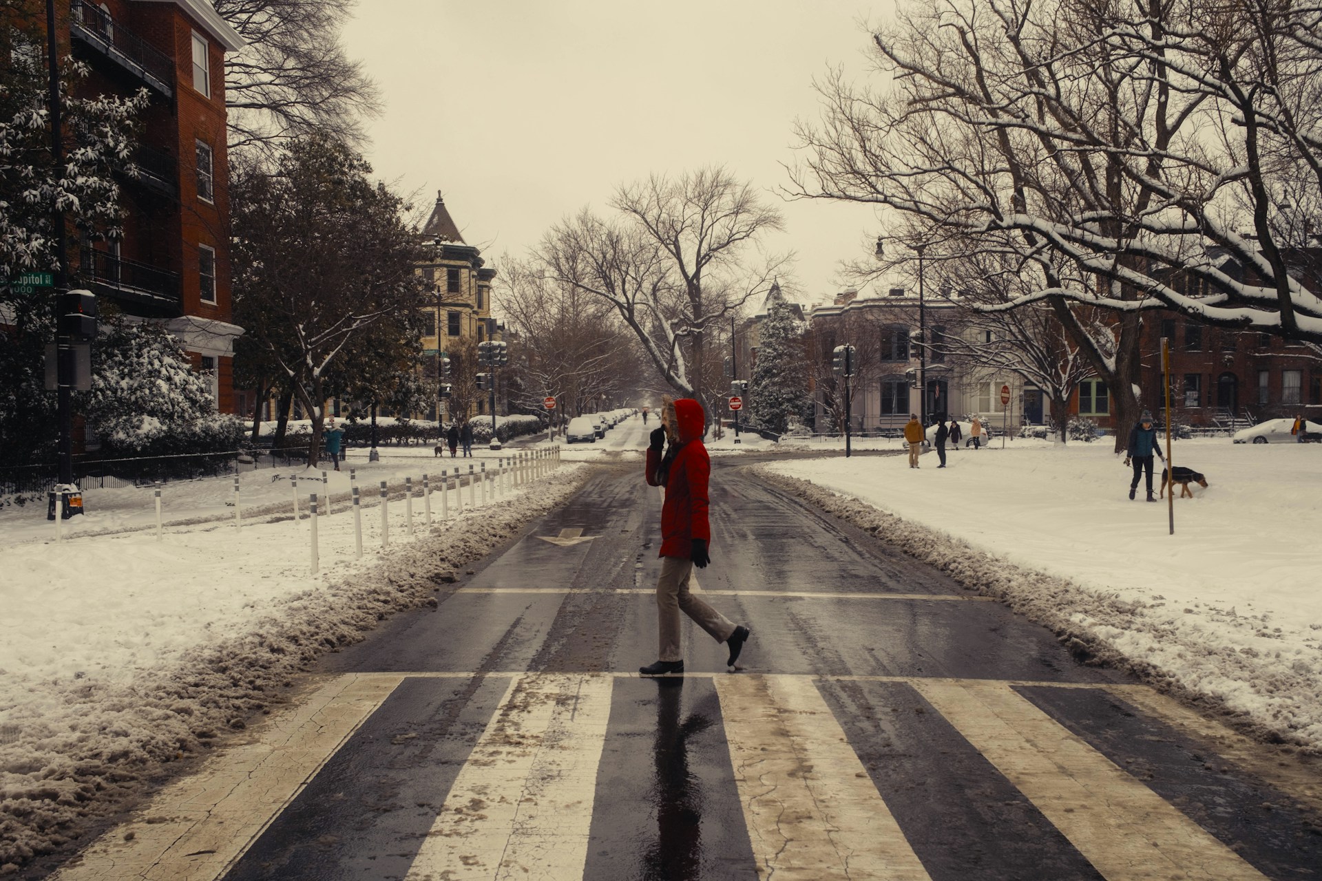 A person in a red coat is walking down a snowy street