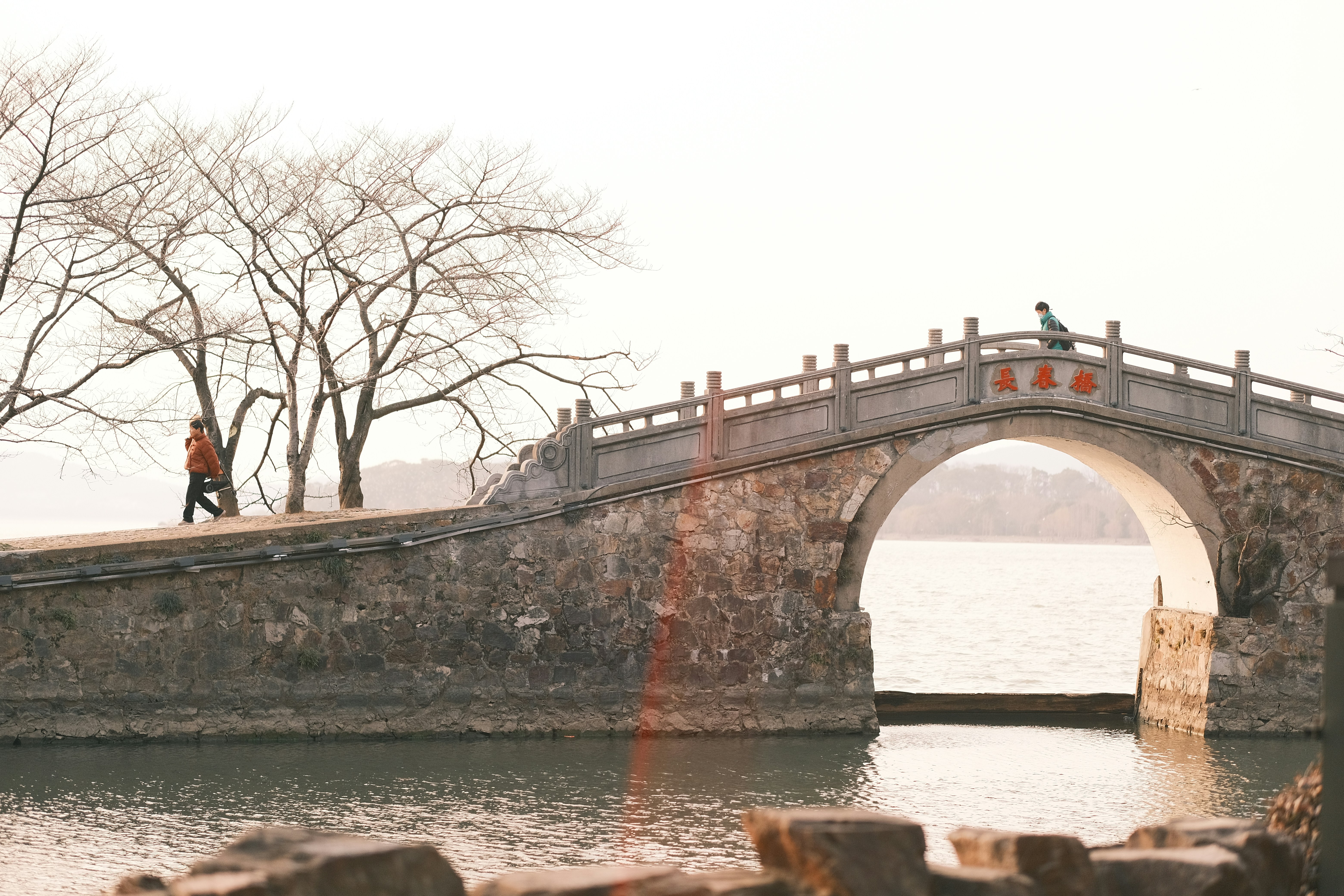 Ein Mann geht über eine Brücke über ein Gewässer