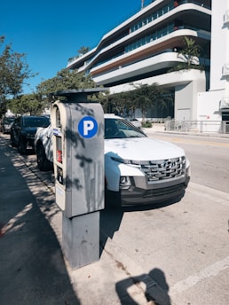 A white car parked next to a parking meter