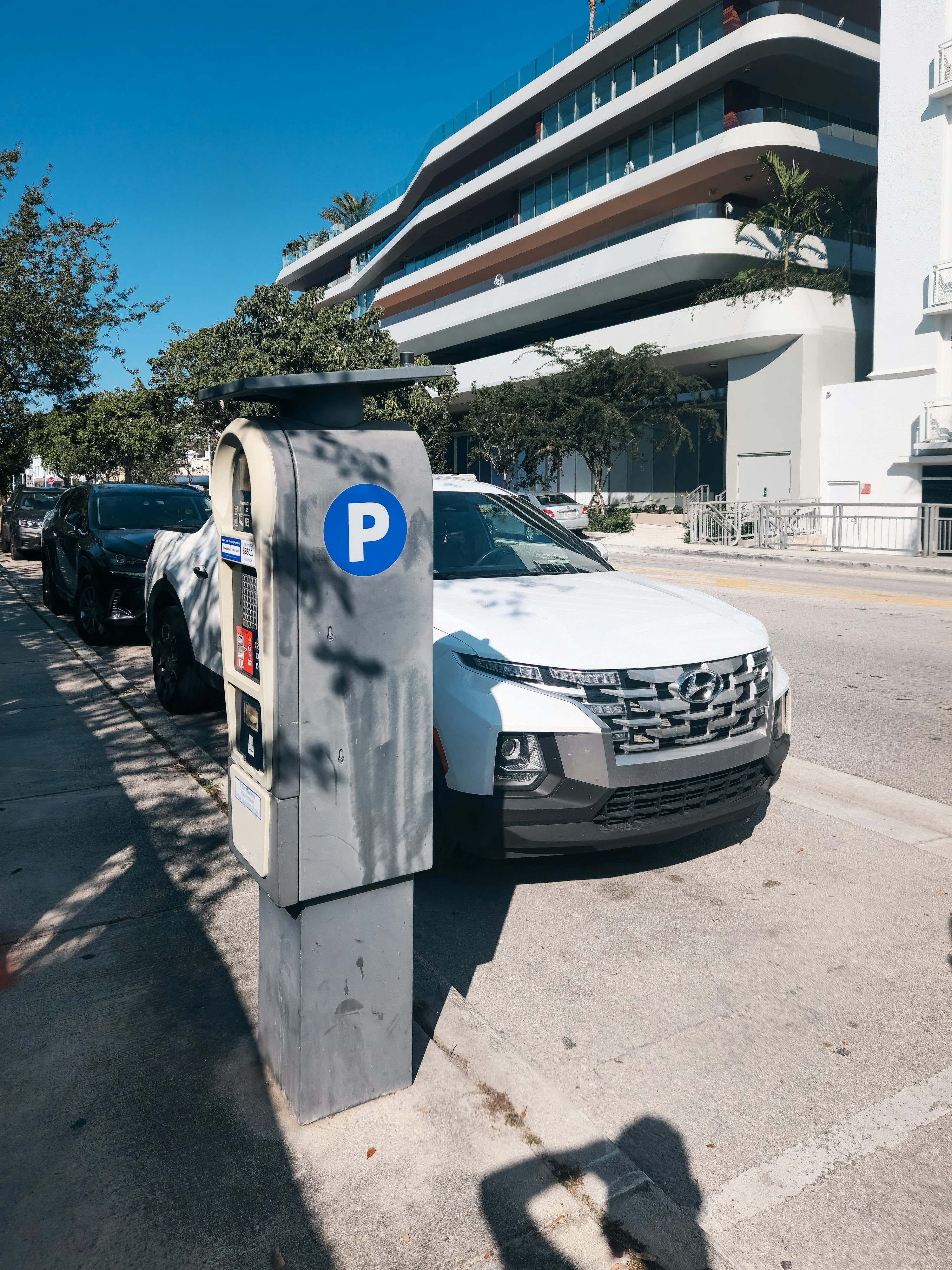 A white car parked next to a parking meter