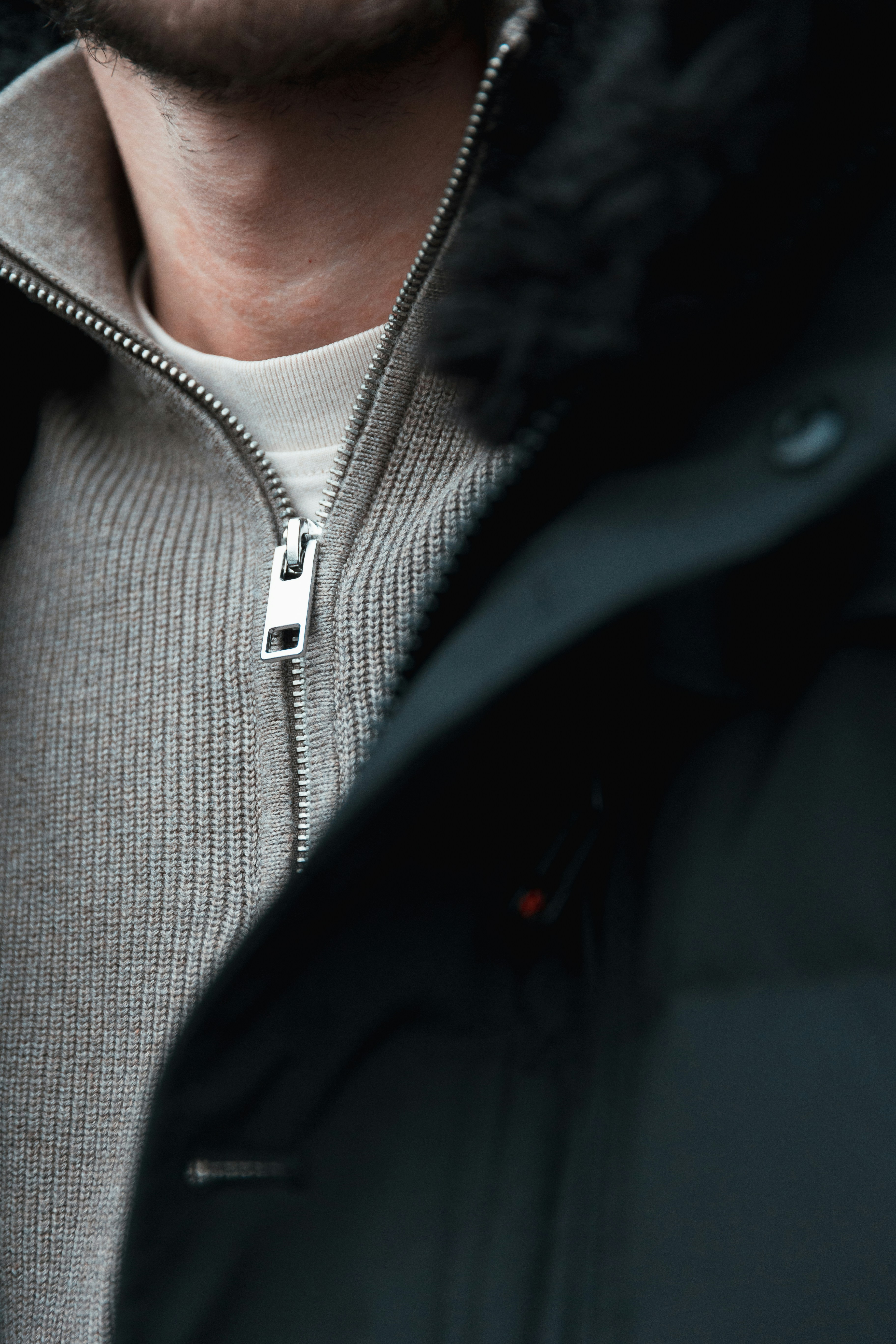 Un hombre vestido con una chaqueta negra y un suéter gris