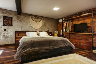 A bedroom with a bed, dresser and television