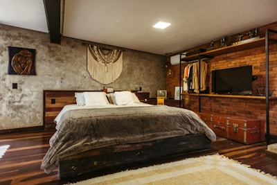 A bedroom with a bed, dresser and television